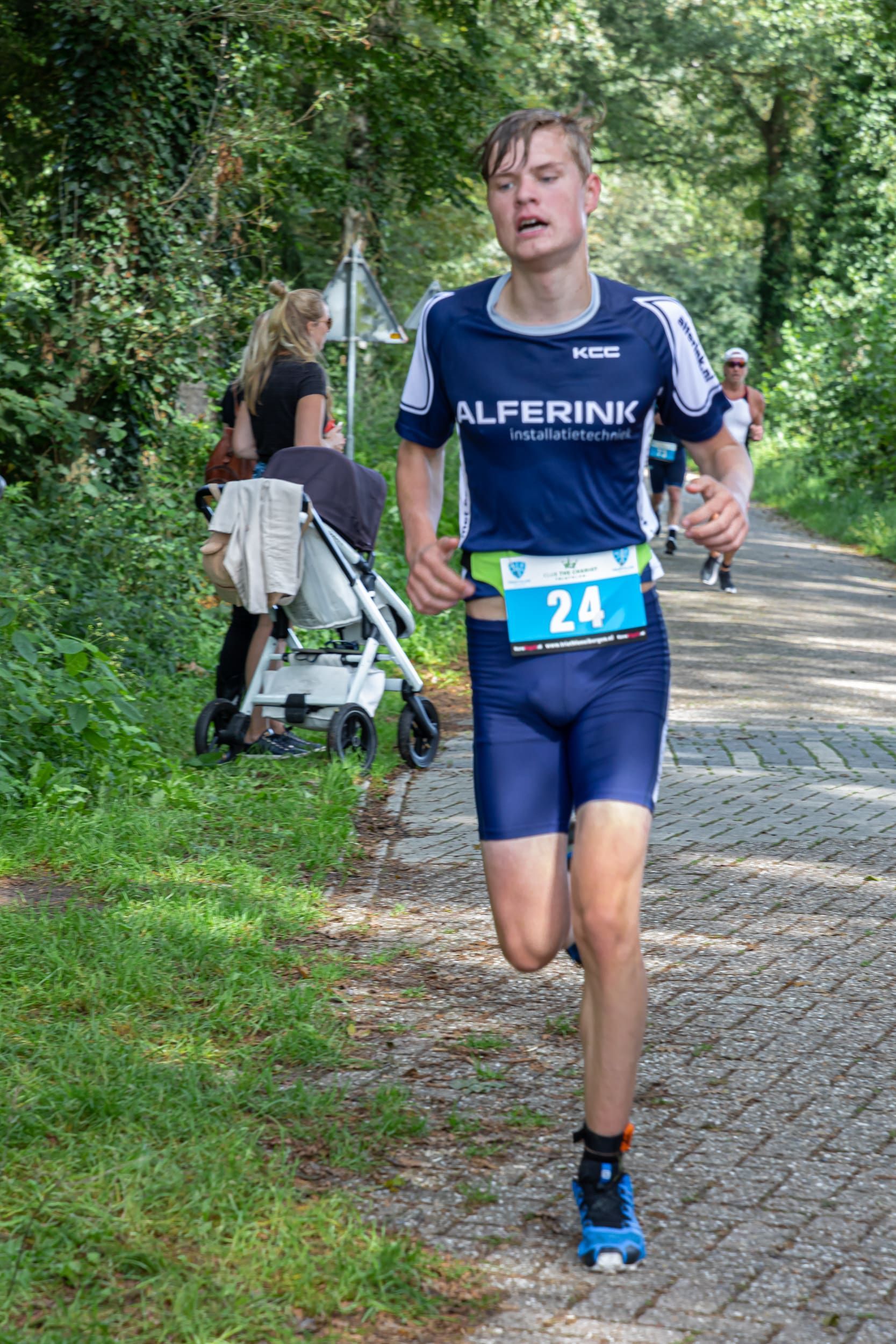 Een jongeman rent over een geplaveide weg.