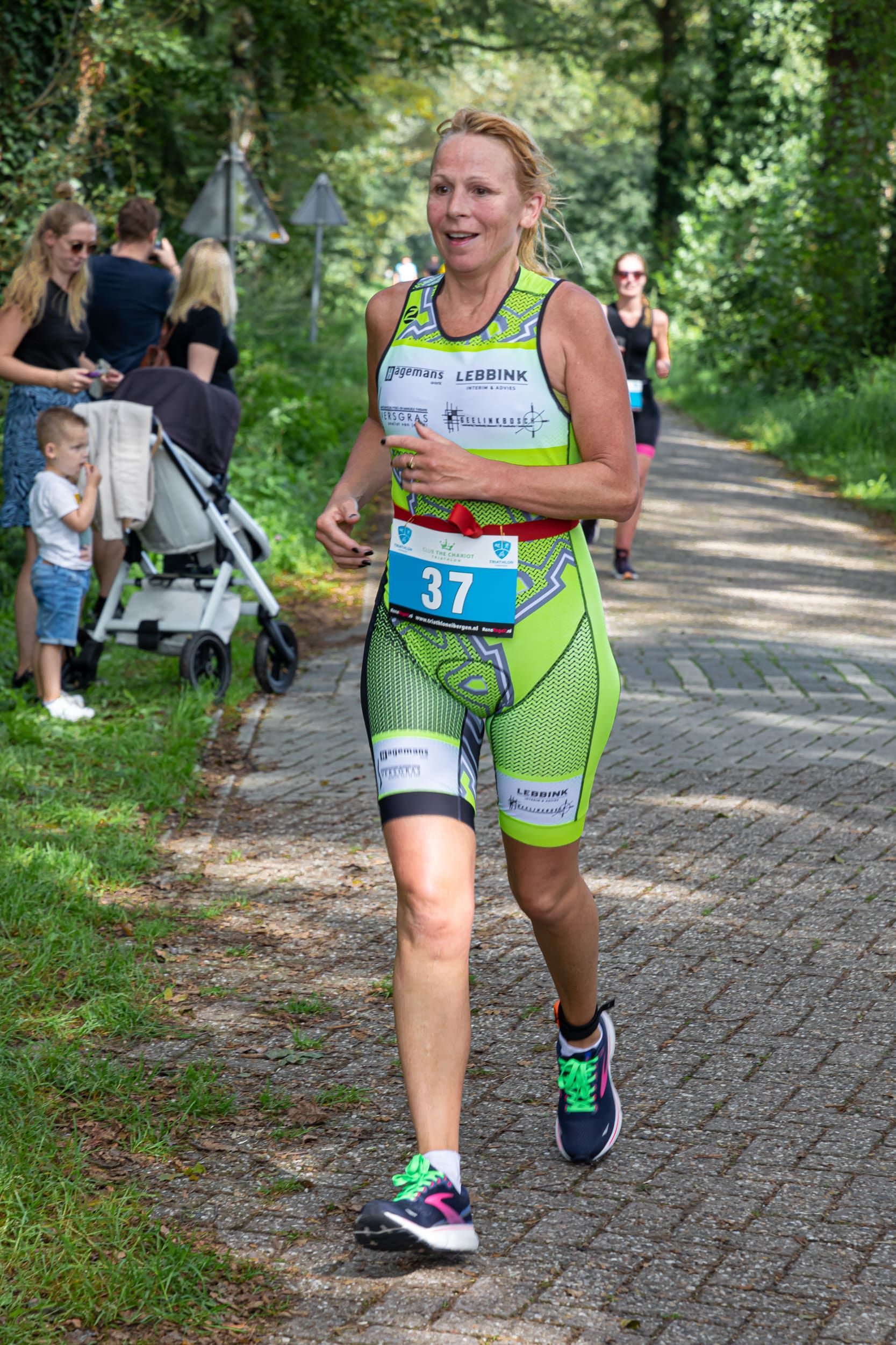 Een vrouw rent over de weg, met op de achtergrond een kinderwagen.