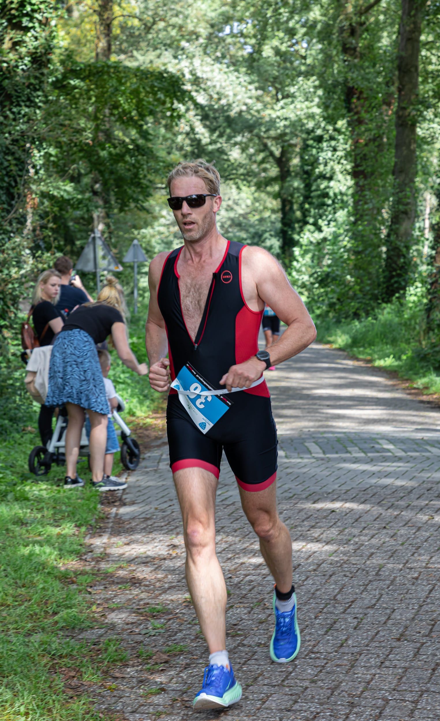 Een man in een triatlonpak rent over de weg.