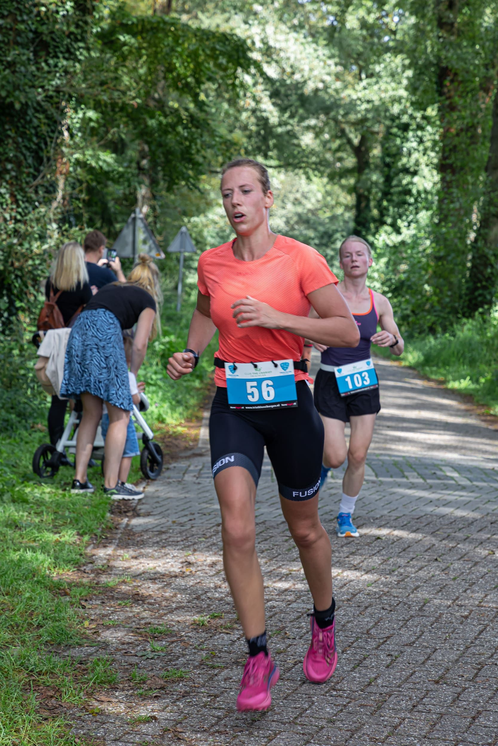 Een vrouw rent een marathon op een onverharde weg.