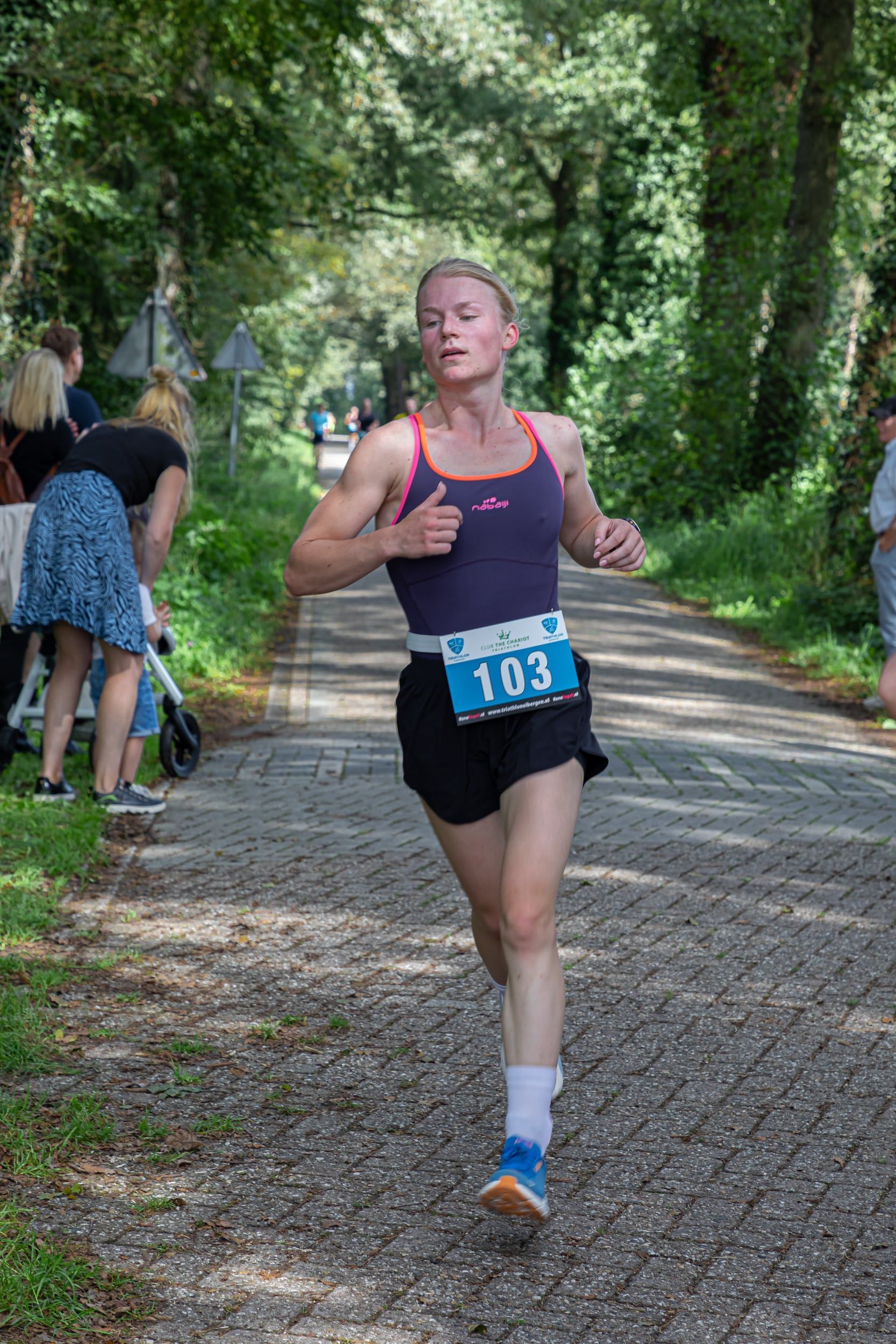 Een vrouw rent een marathon op een onverharde weg.