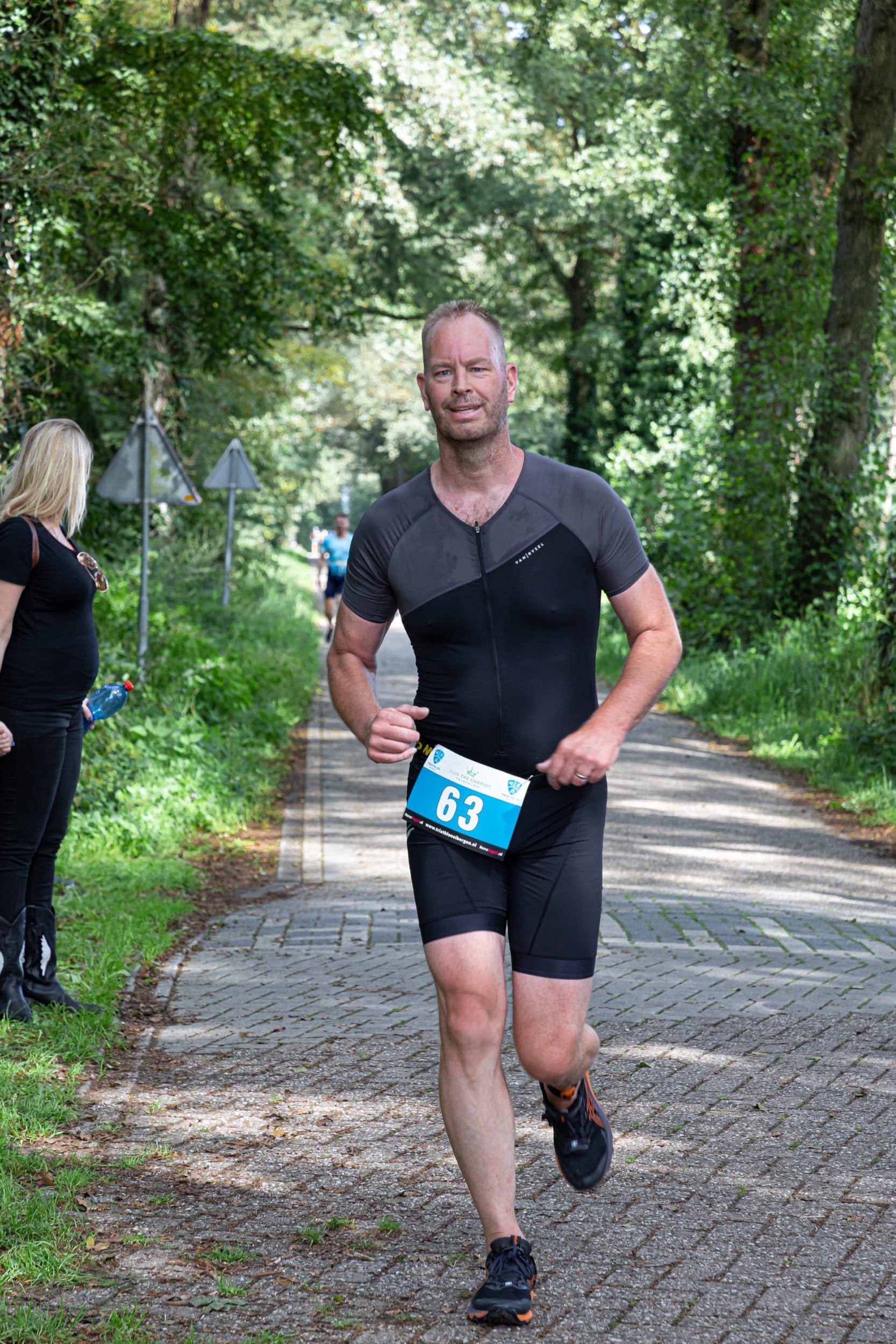 Een man rent over de weg met een blauw label om zijn middel.