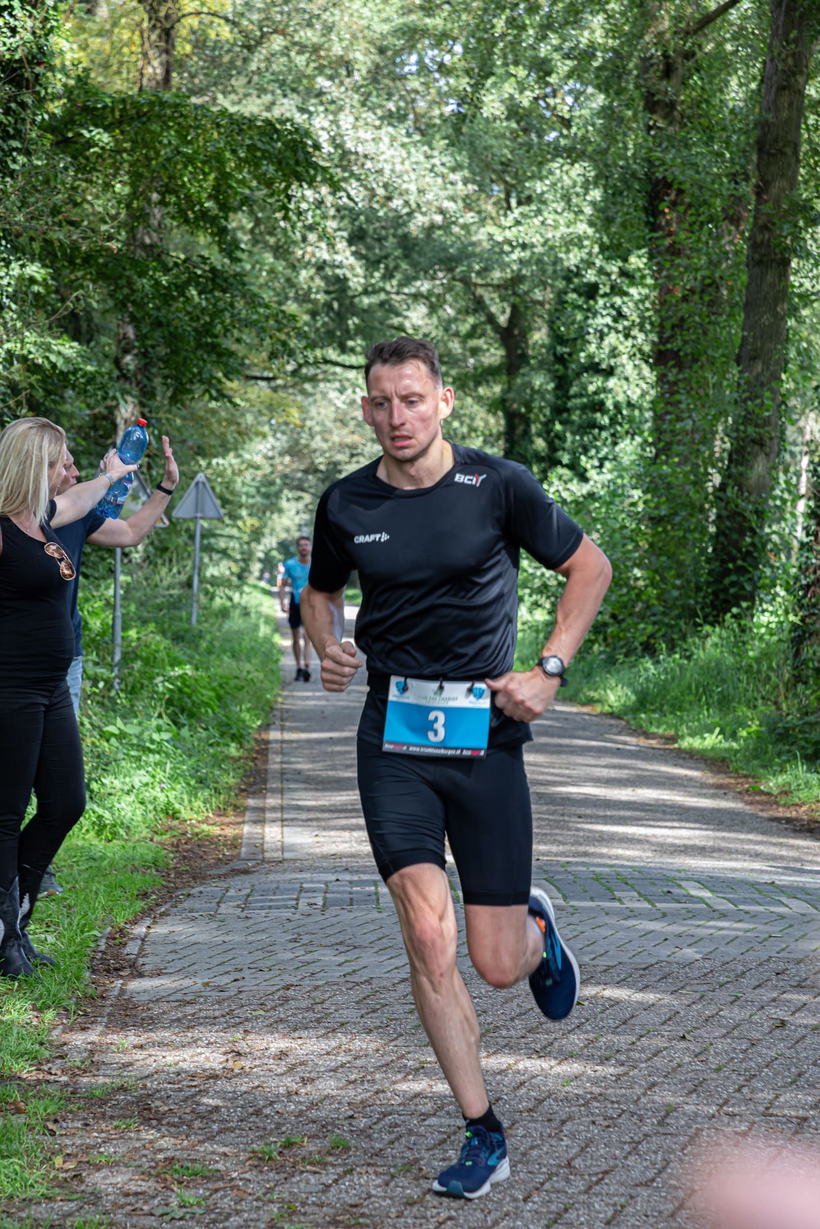 Een man rent een marathon op een onverharde weg.