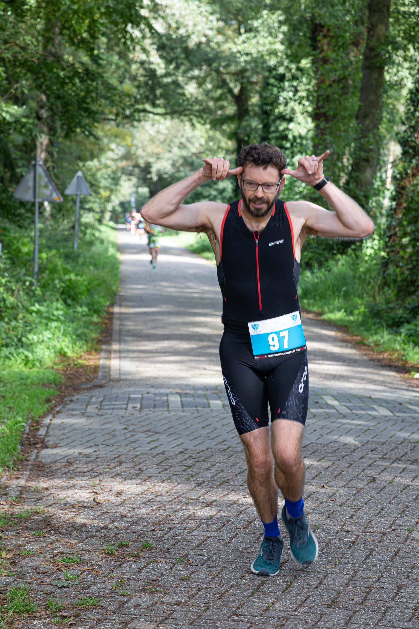 Een man rent over een onverharde weg en houdt zijn handen voor zijn oren.