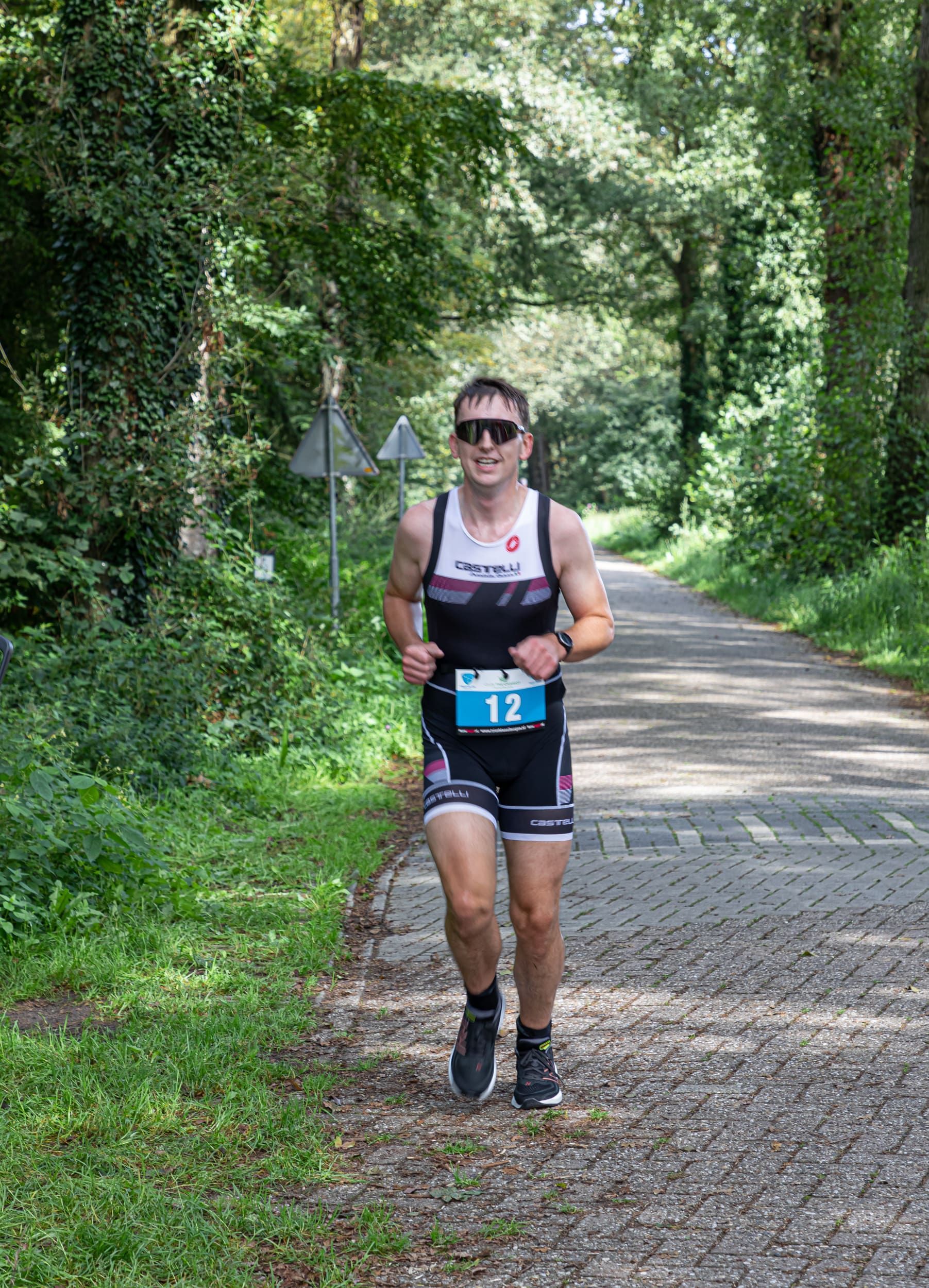 Een man rent over een onverharde weg in het bos.