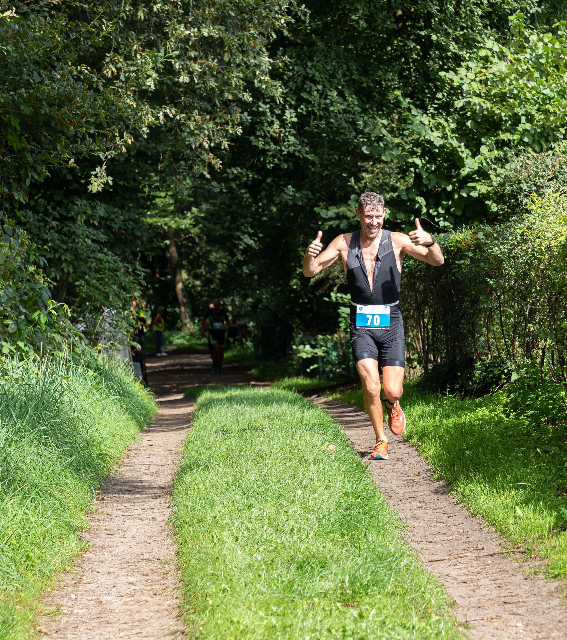 Een man rent over een zandpad in het bos.