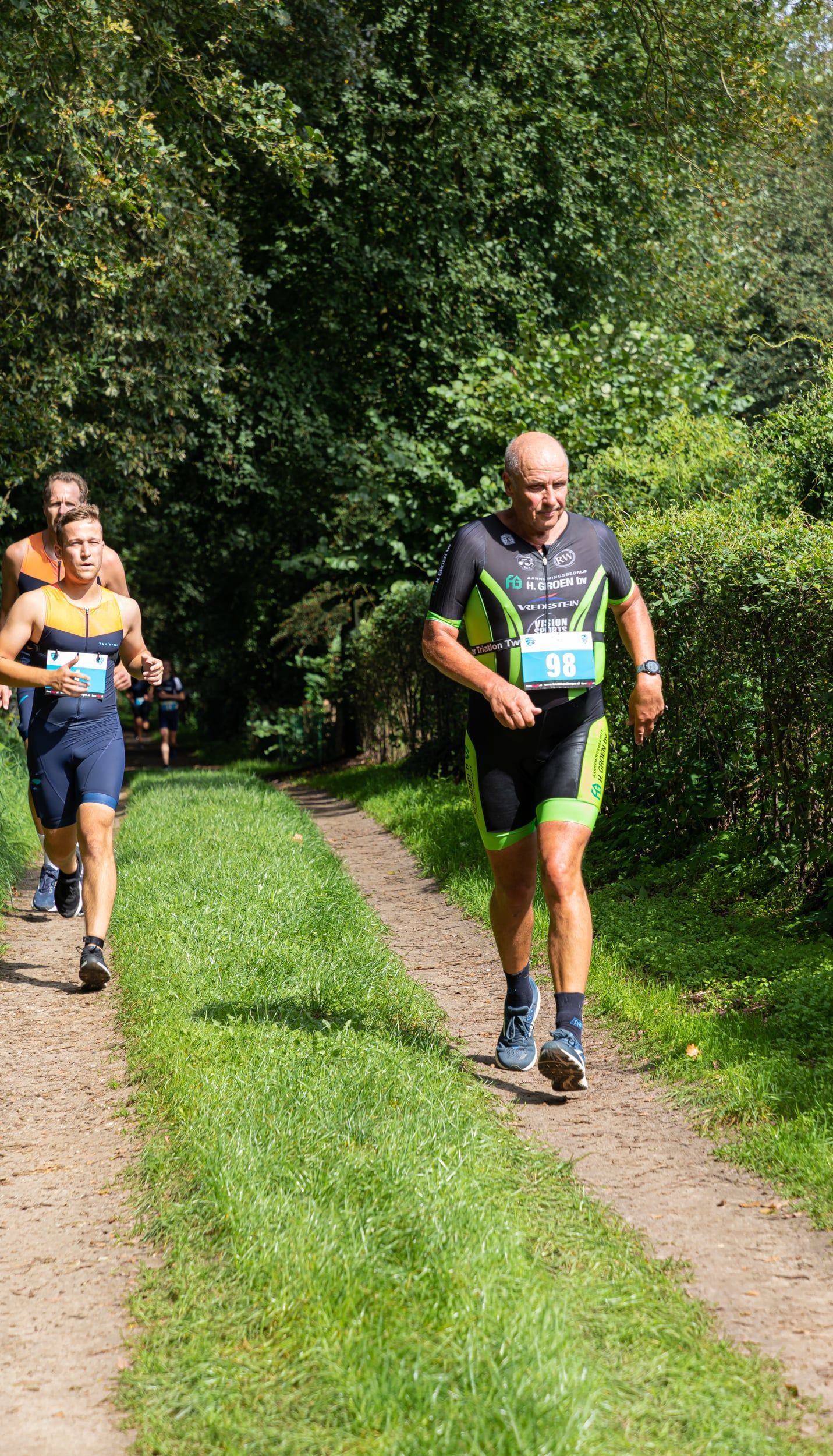 Een groep mannen rent over een pad in het bos.