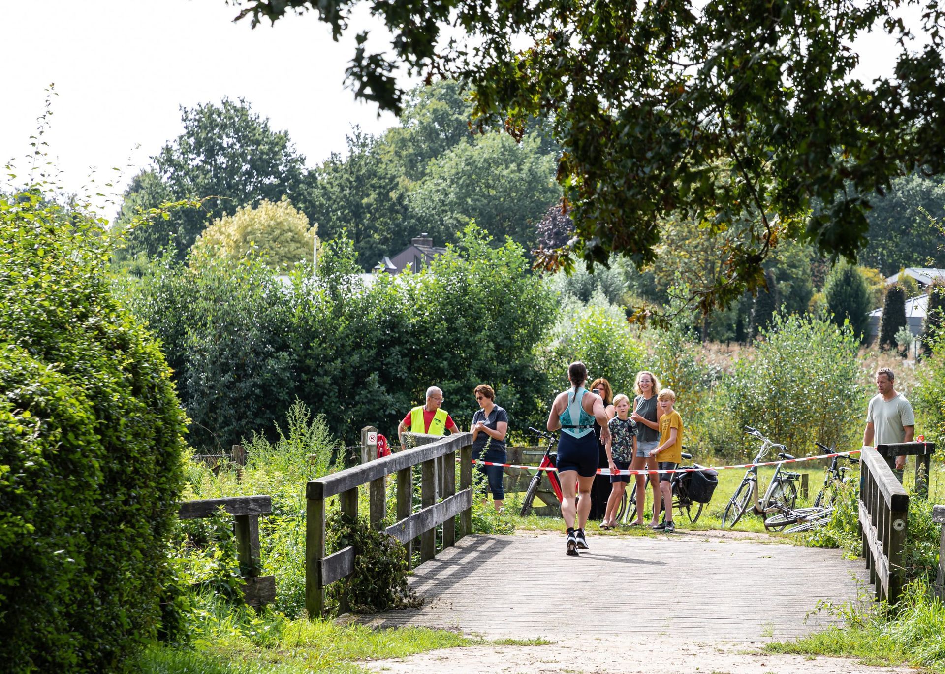 Een groep mensen rent over een brug in een park.