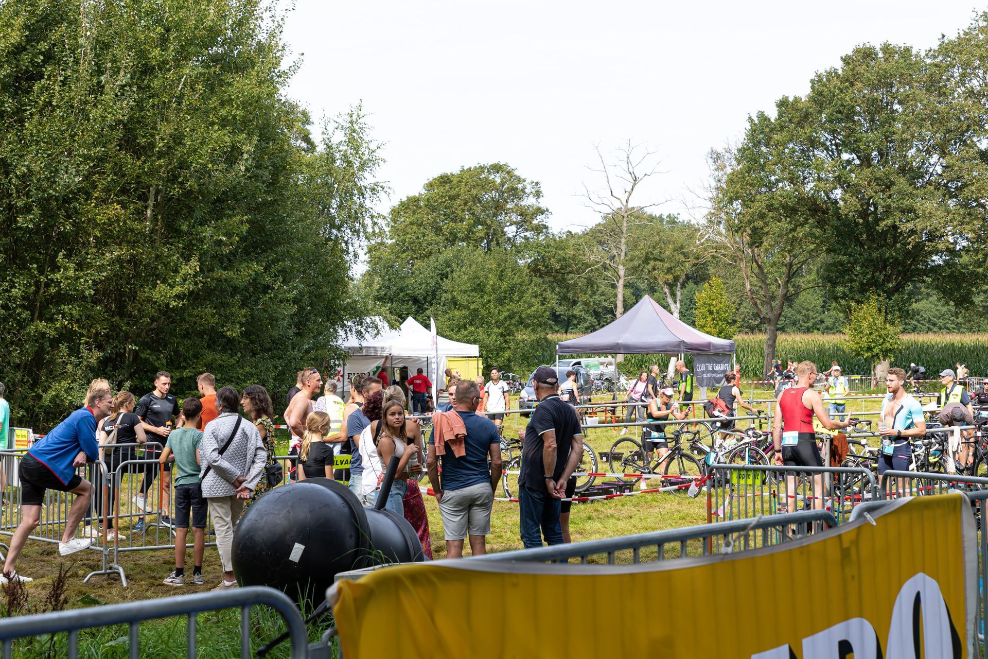 Een groep mensen staat in een veld achter een hek.