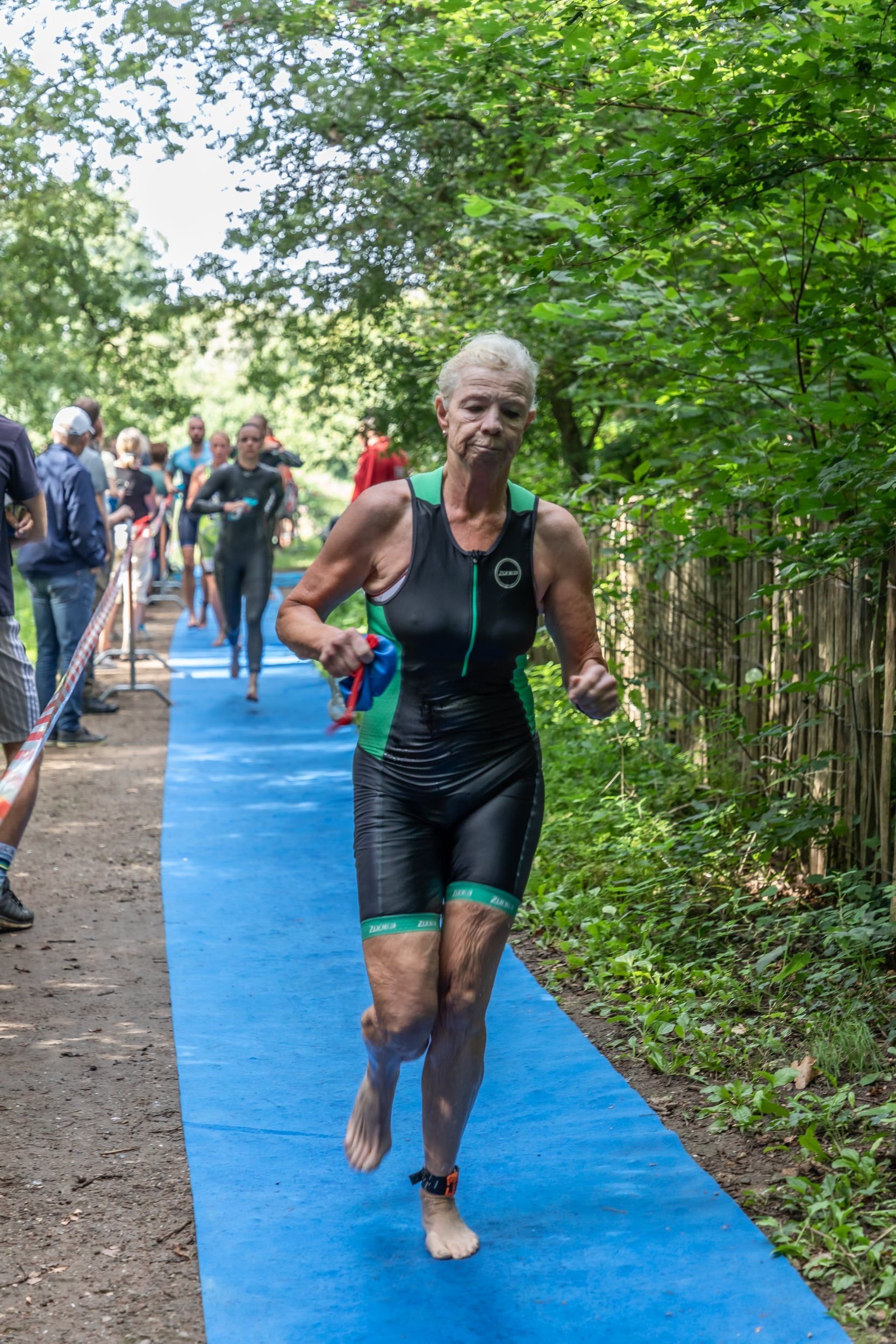 Een vrouw rent op een blauw pad in het bos.