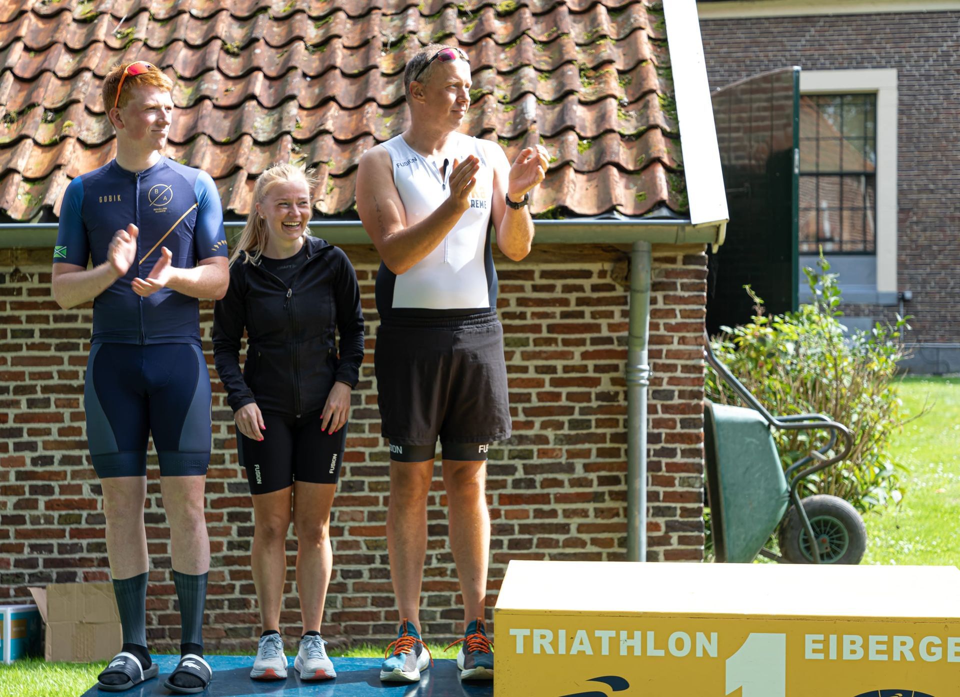 Prijsuitreiking Triathlon Eibergen 2023. Een groep mensen die voor een bord staat met de tekst triatlon