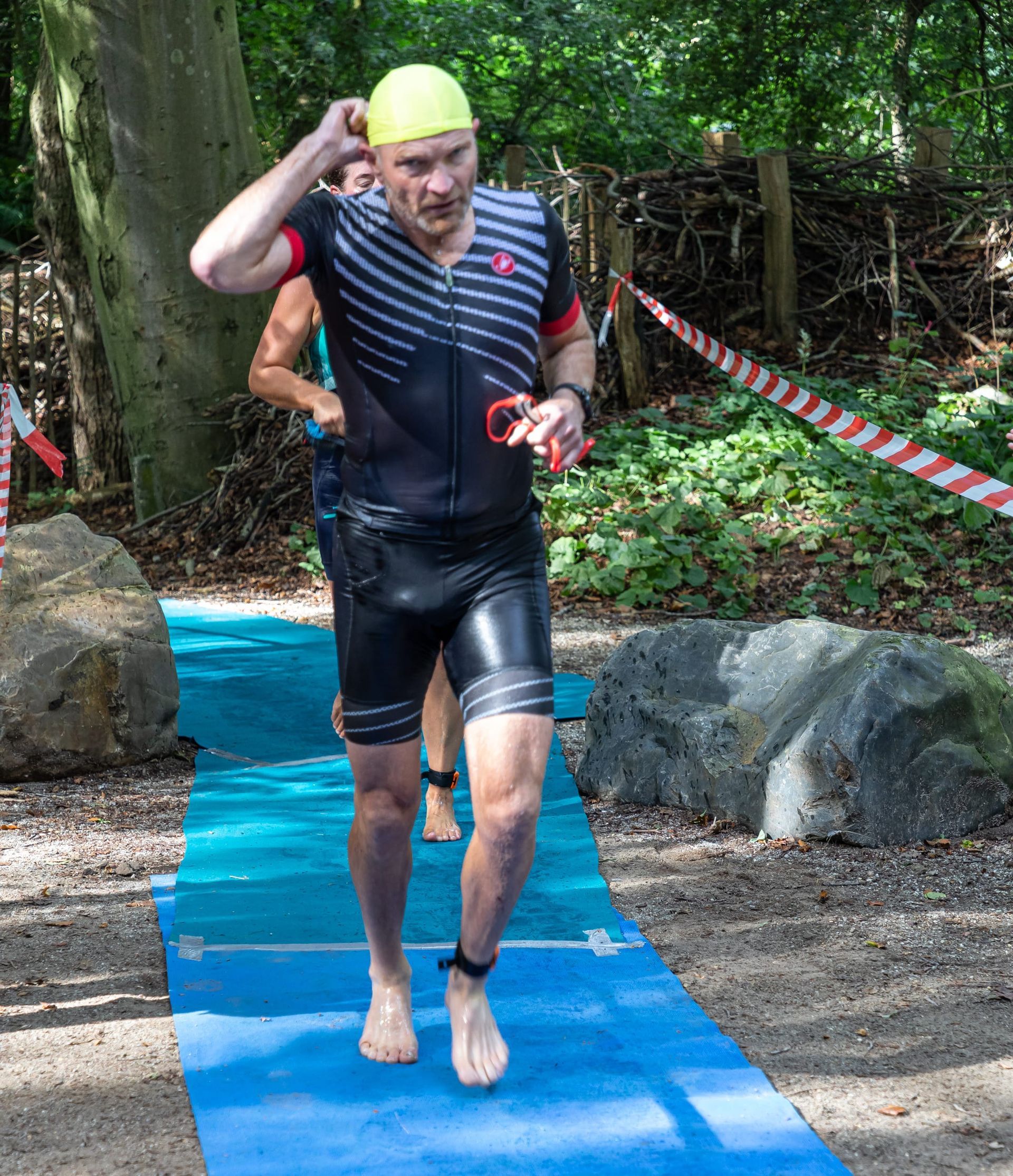 Een man rent op een blauwe mat in het bos.