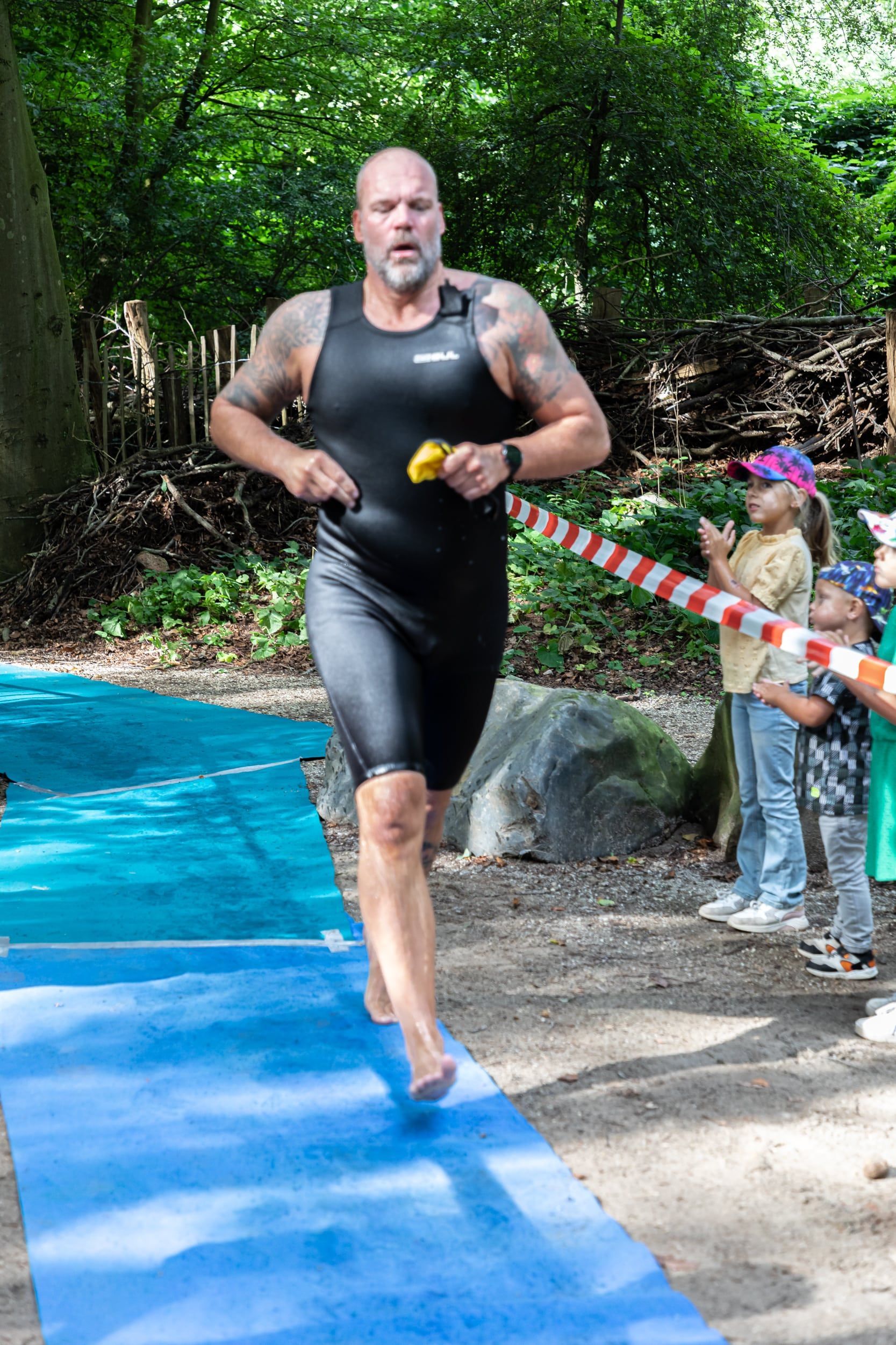 Een man rent op een blauwe mat in het bos.