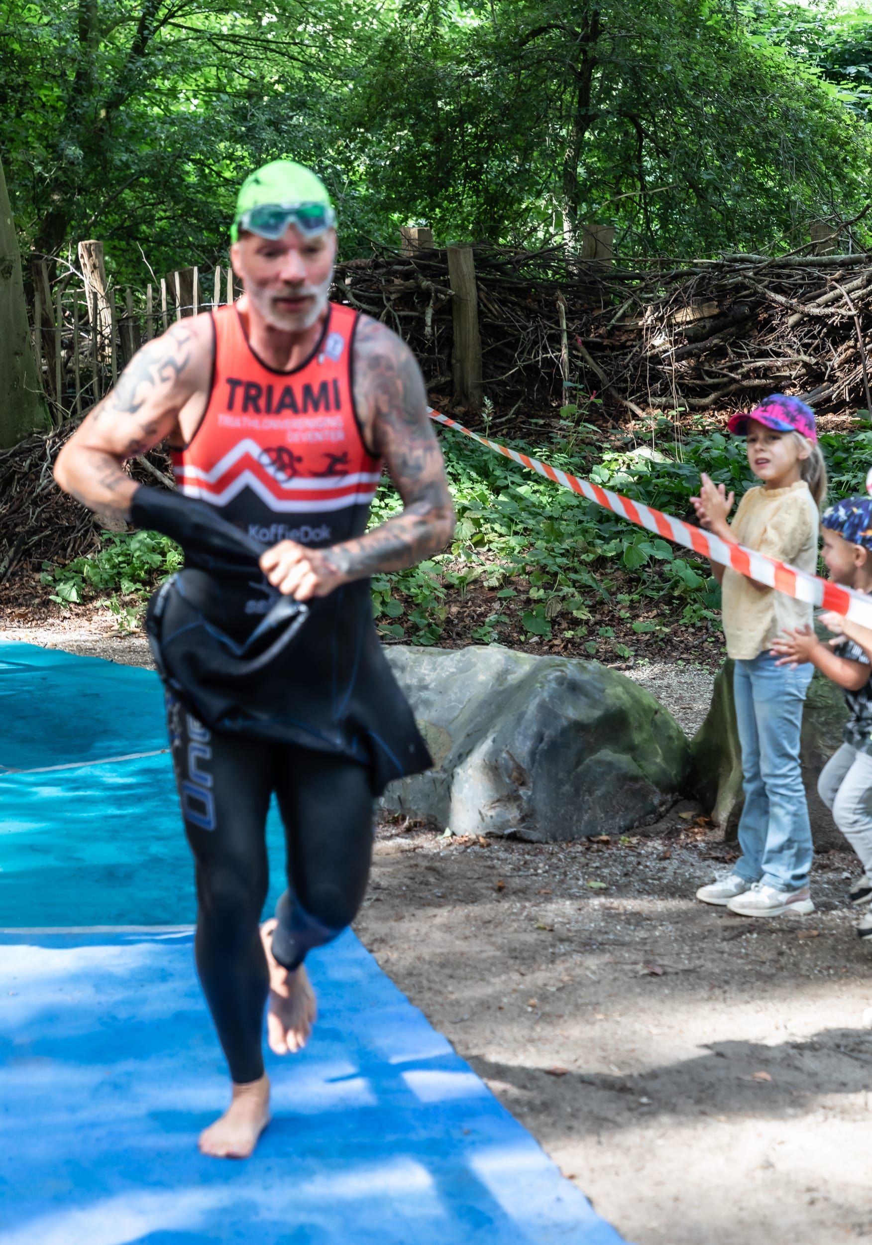 Een man in een triatlonpak maakt zich klaar om te gaan zwemmen.