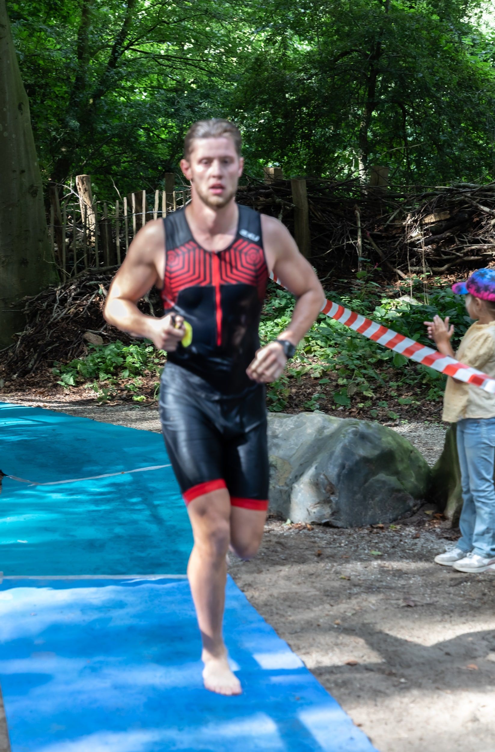 Een man rent op een blauwe mat in het bos.