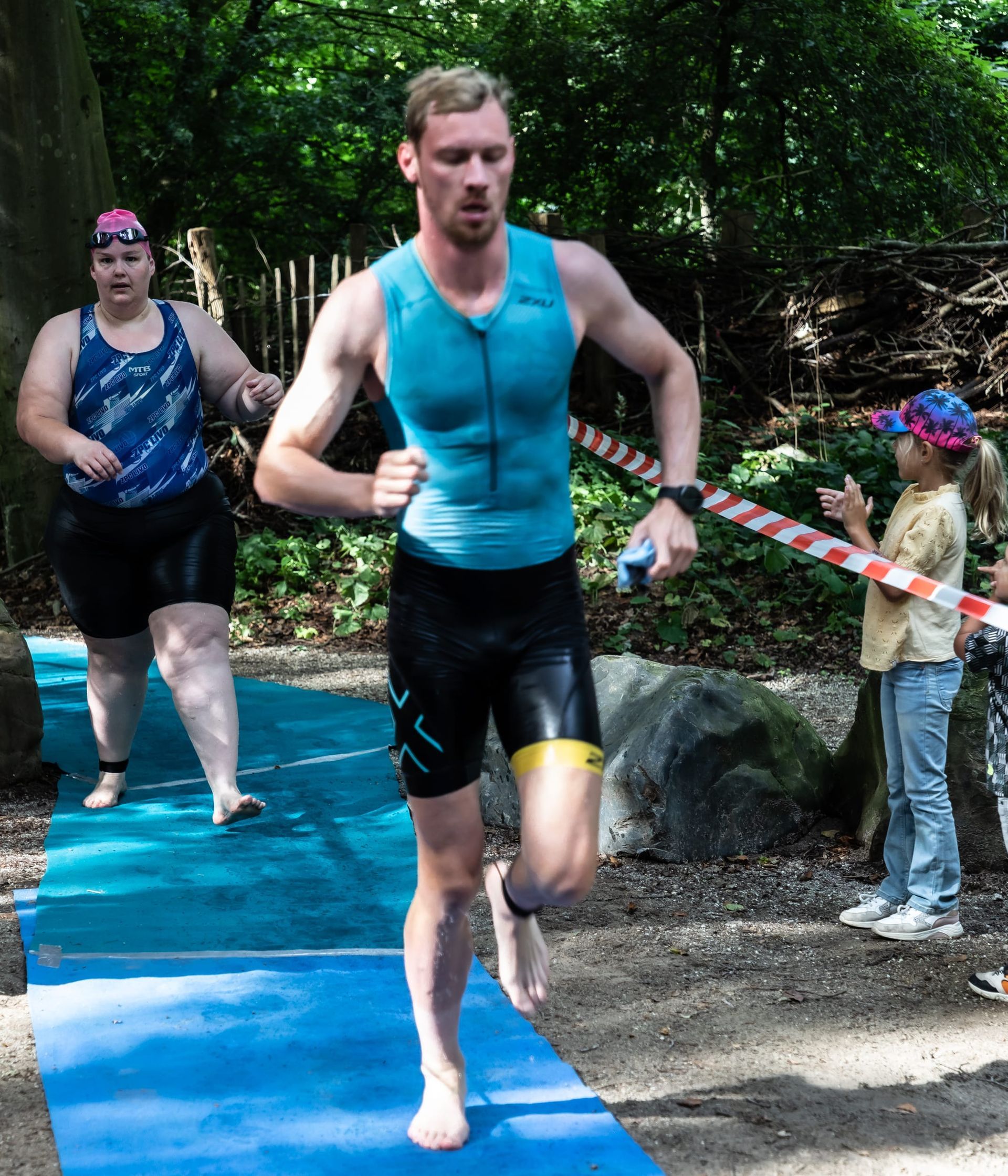 Een man in een blauw tanktopje rent op een blauwe mat