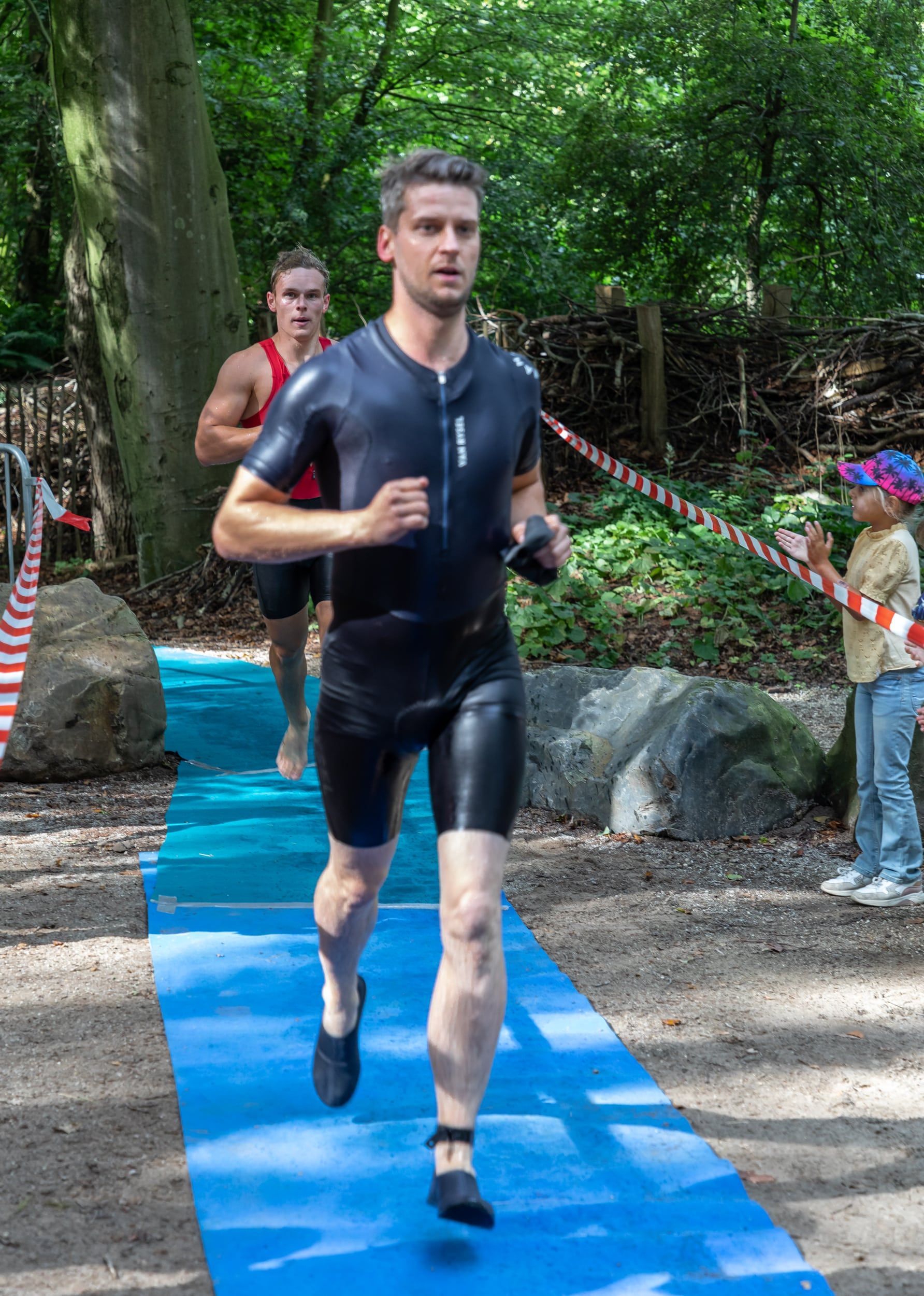 Een man in een wetsuit rent op een blauwe mat