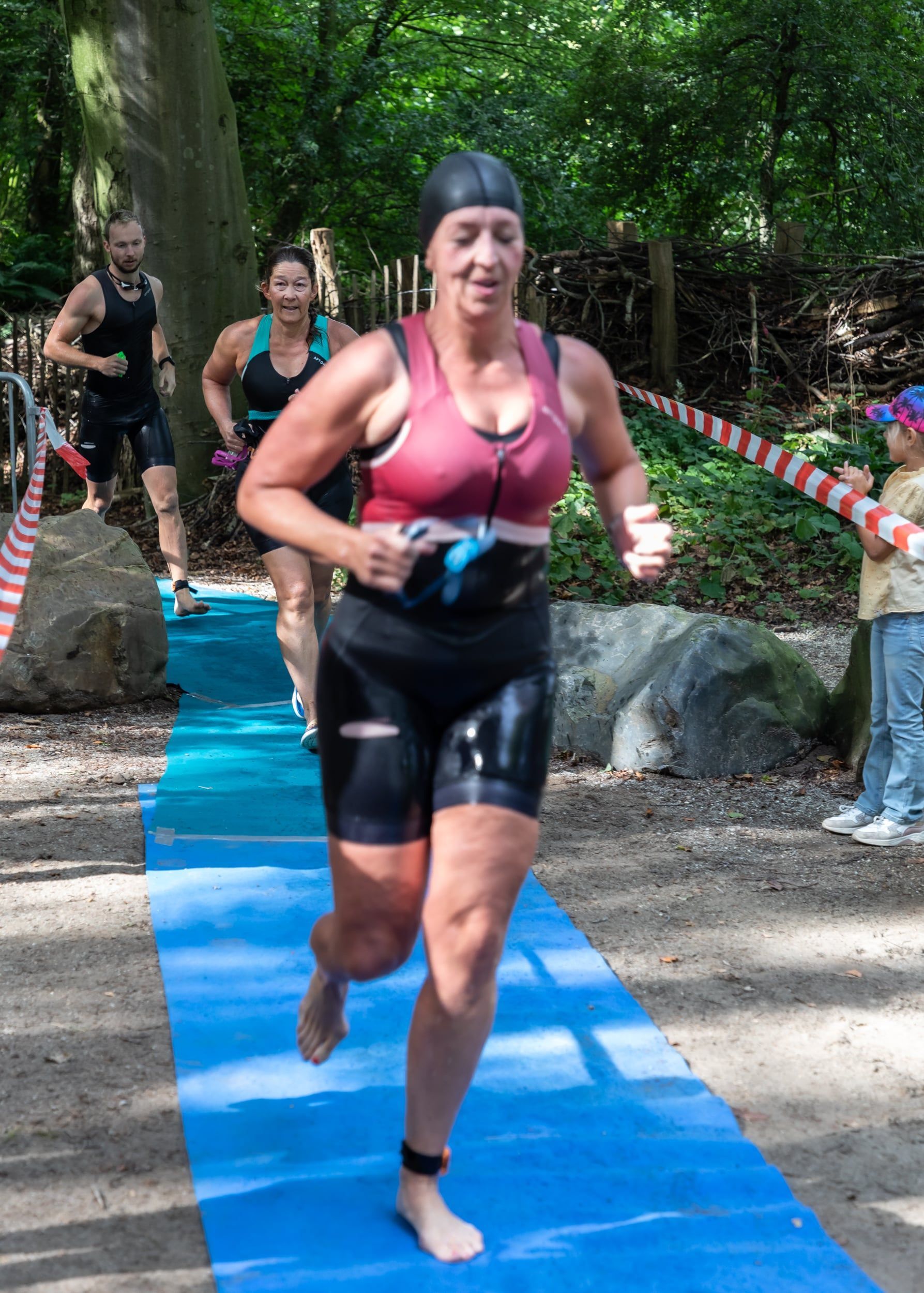 Een vrouw in een wetsuit rent op een blauwe mat