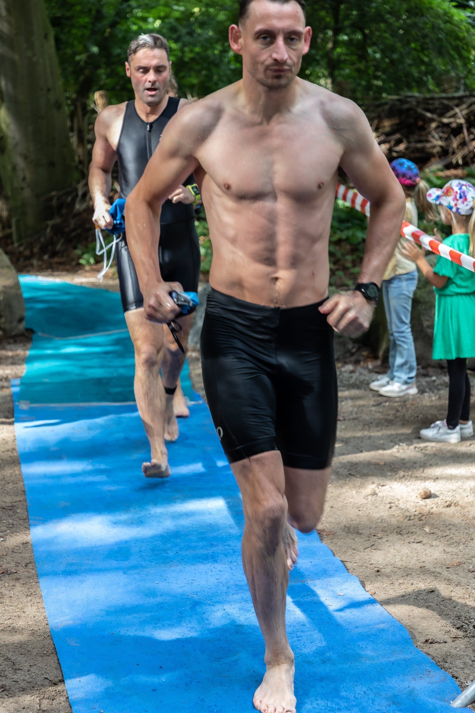 Een man zonder shirt rent op een blauwe mat.