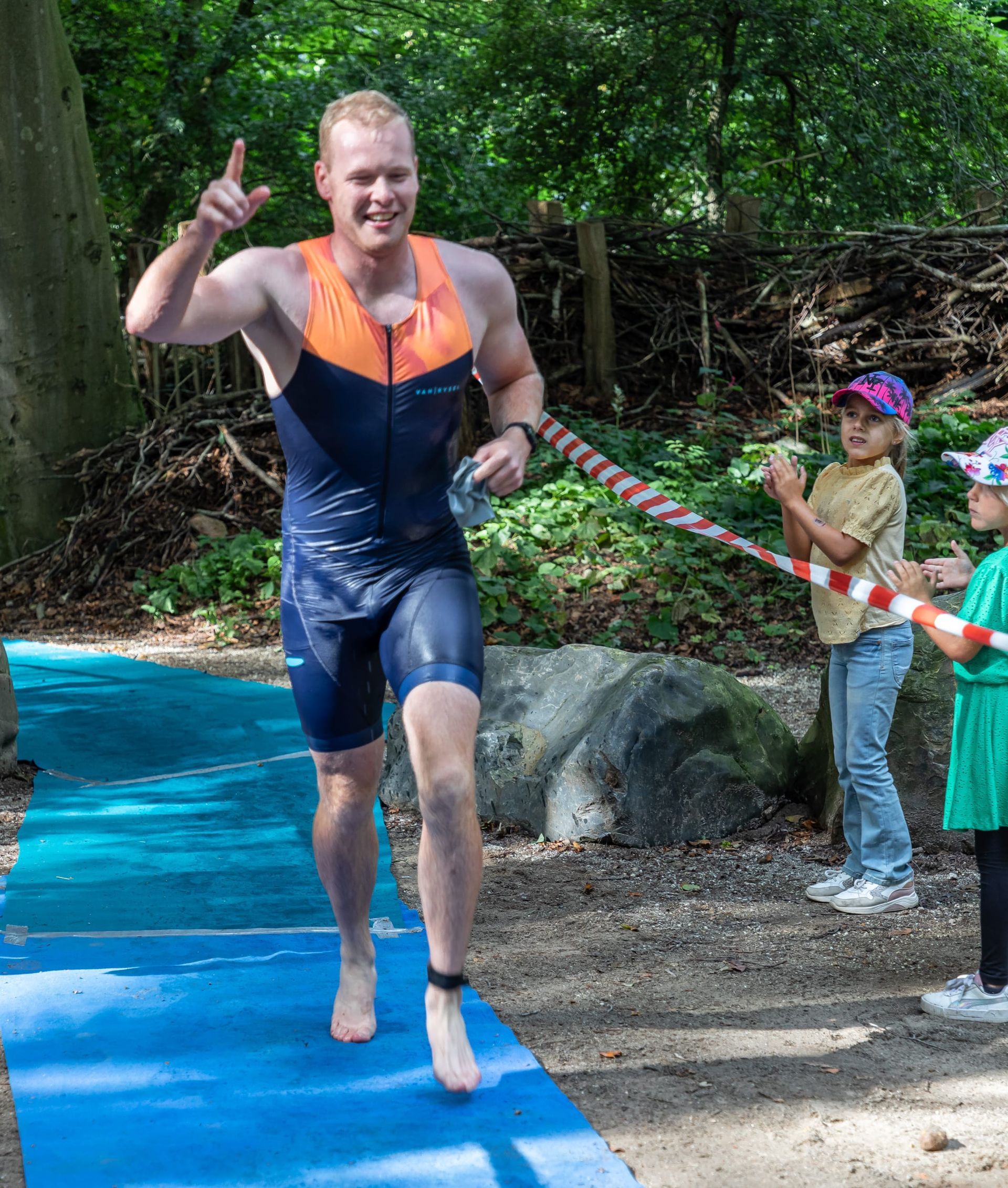 Een man rent op een blauwe mat en steekt zijn duim omhoog