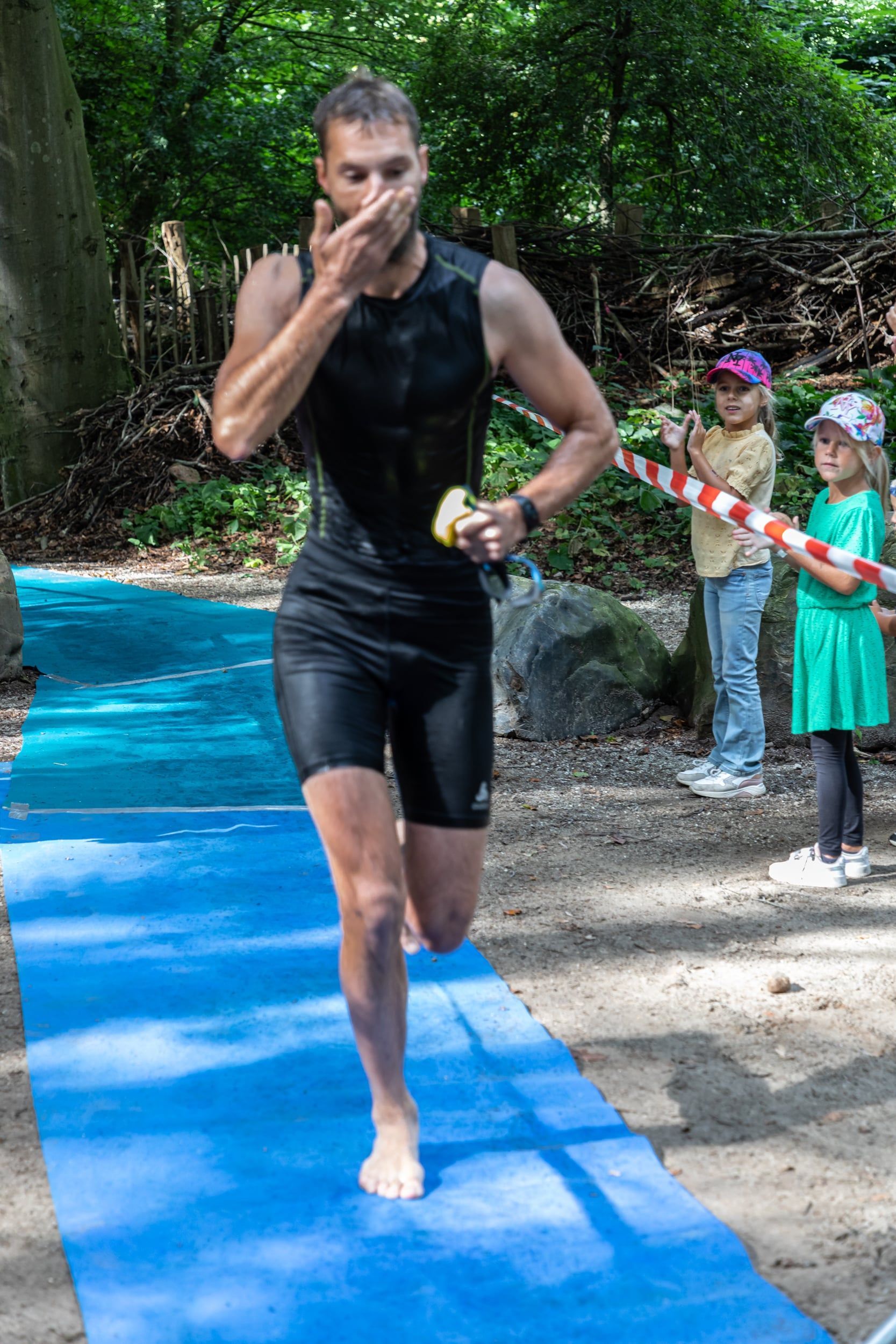 Een man rent op een blauwe mat in het bos.