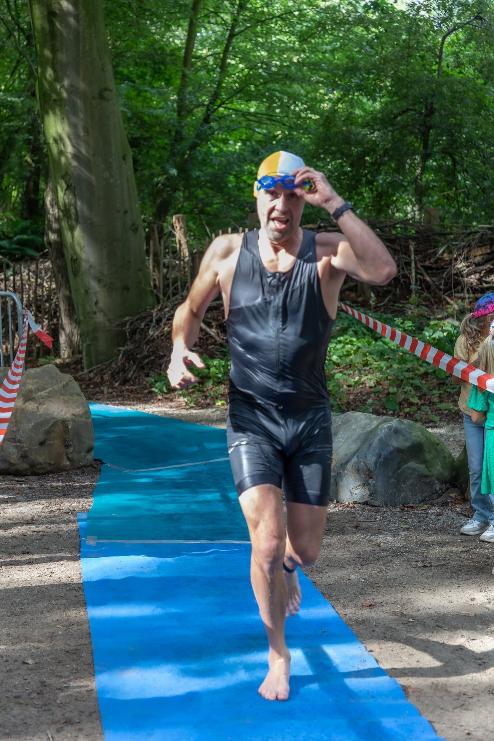 Een man rent op een blauwe mat in het bos.