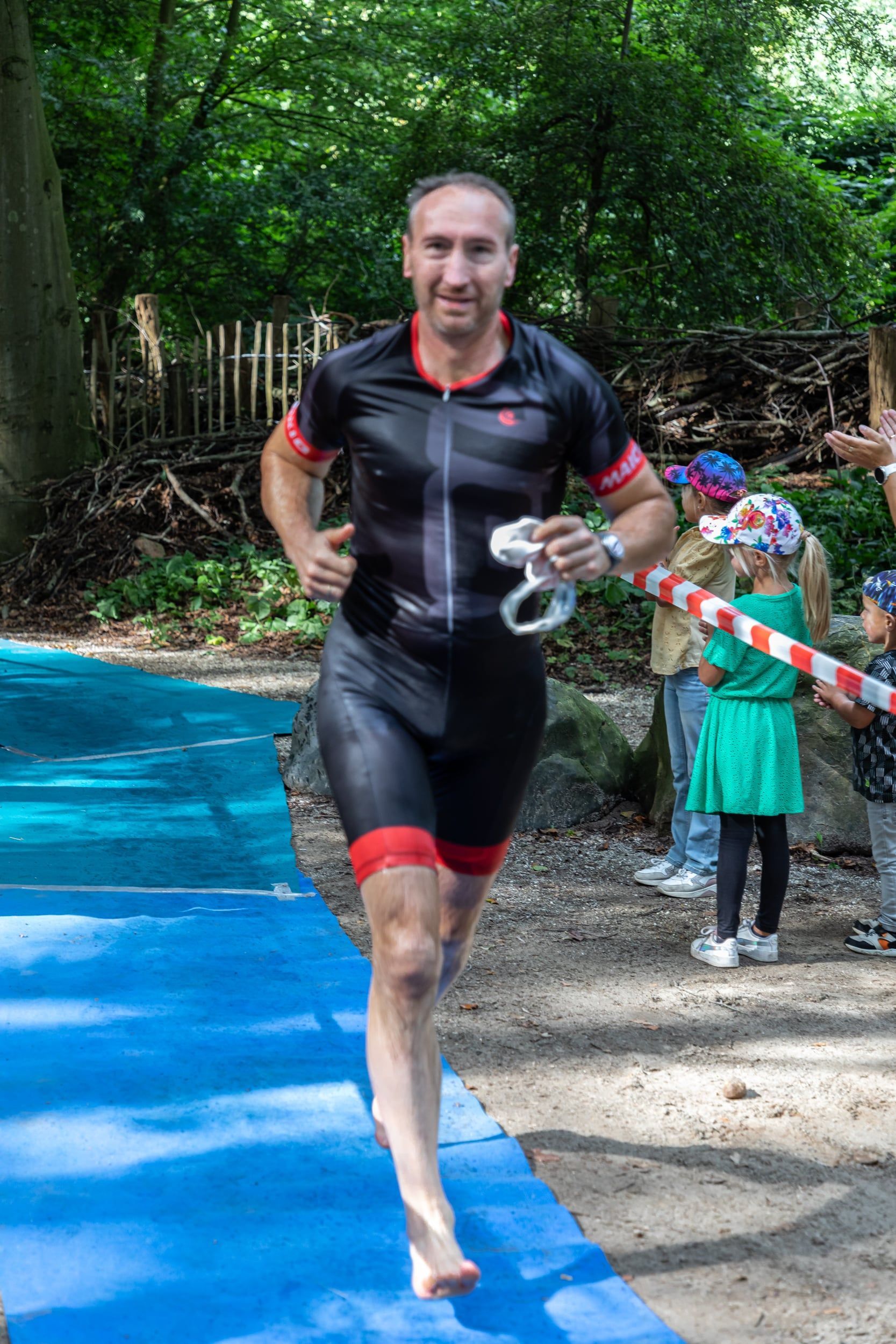 Een man in een wetsuit rent op een blauwe mat.
