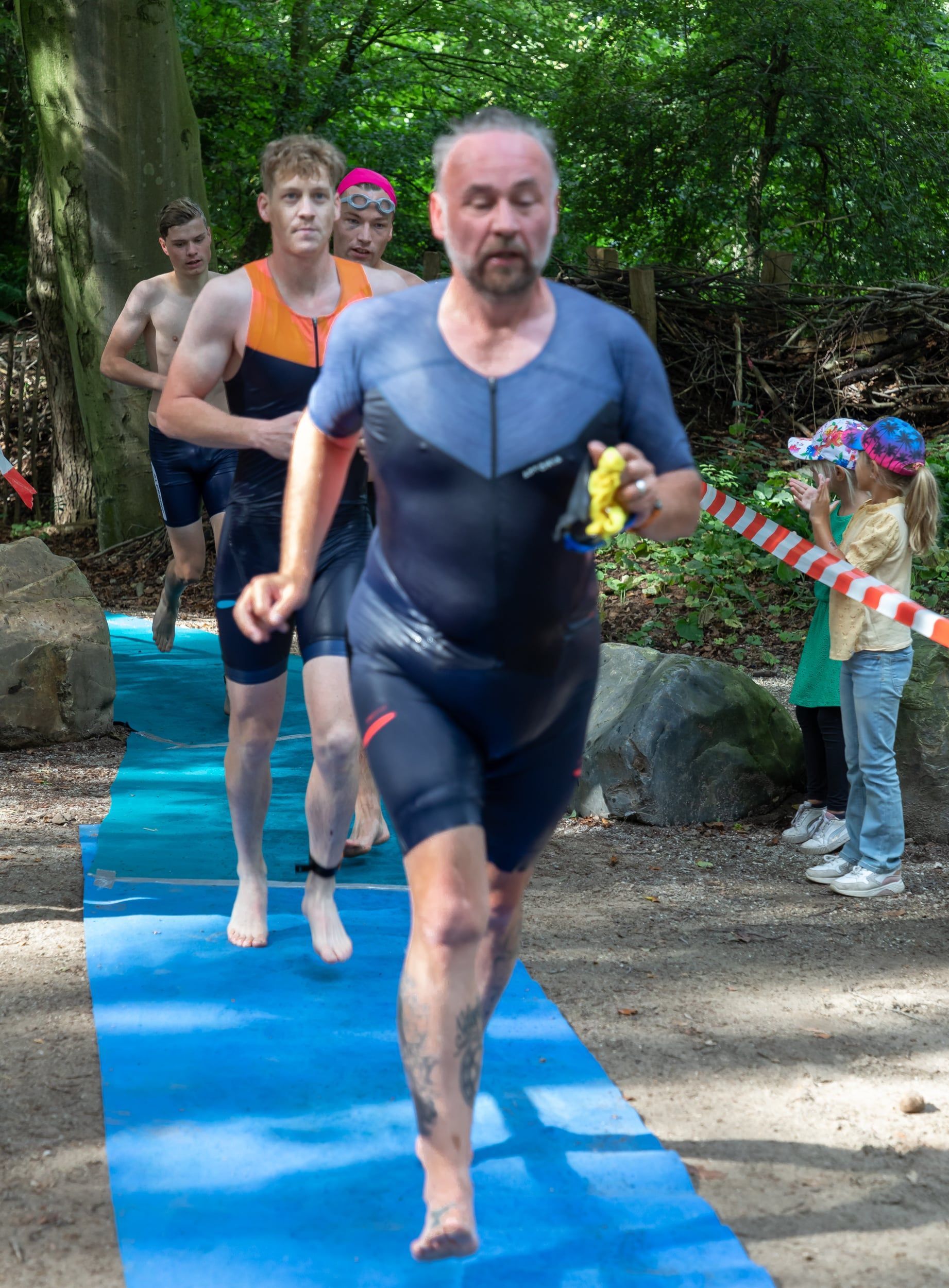 Een man in een wetsuit rent op een blauwe mat