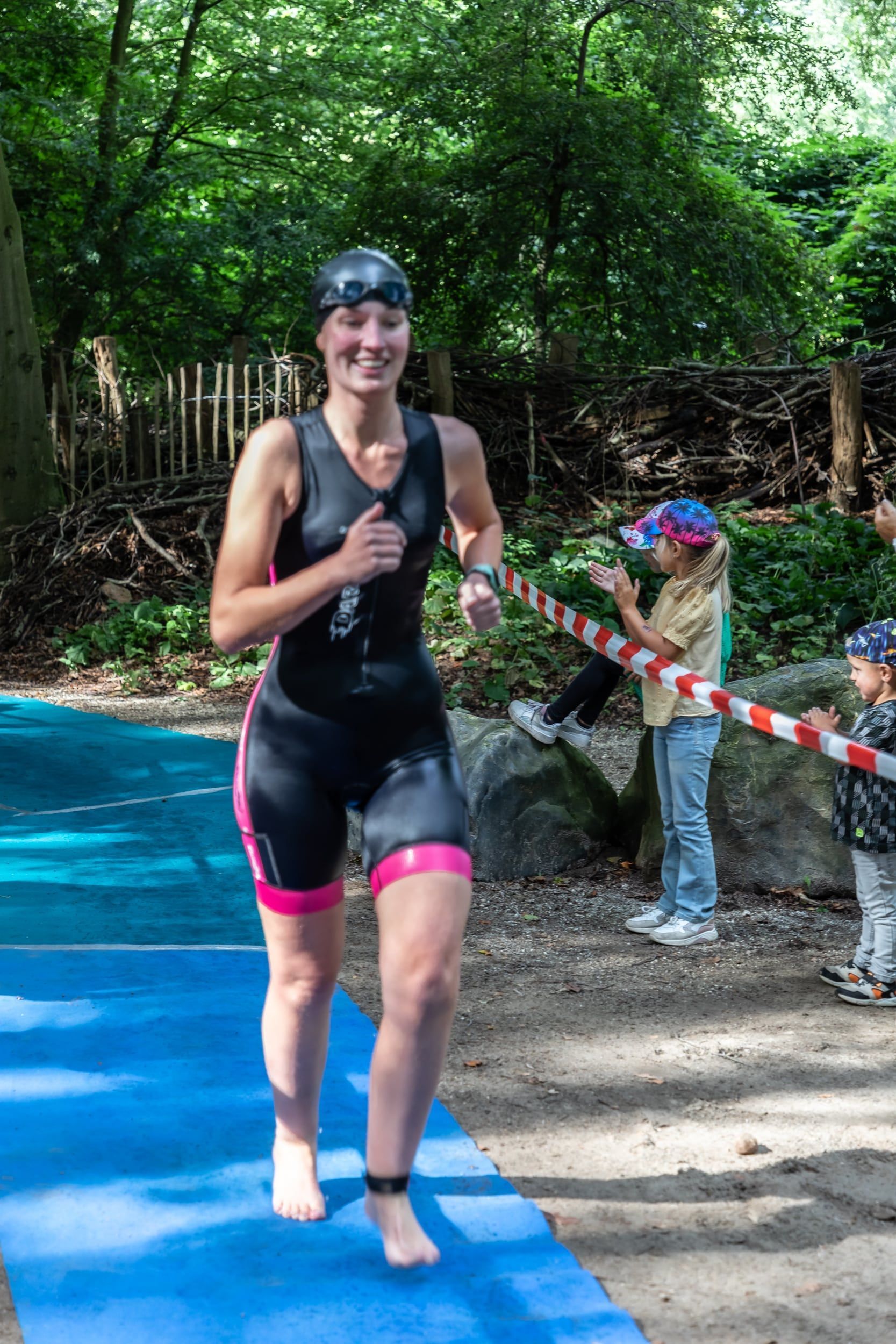 Een vrouw in een wetsuit rent op een blauwe mat.