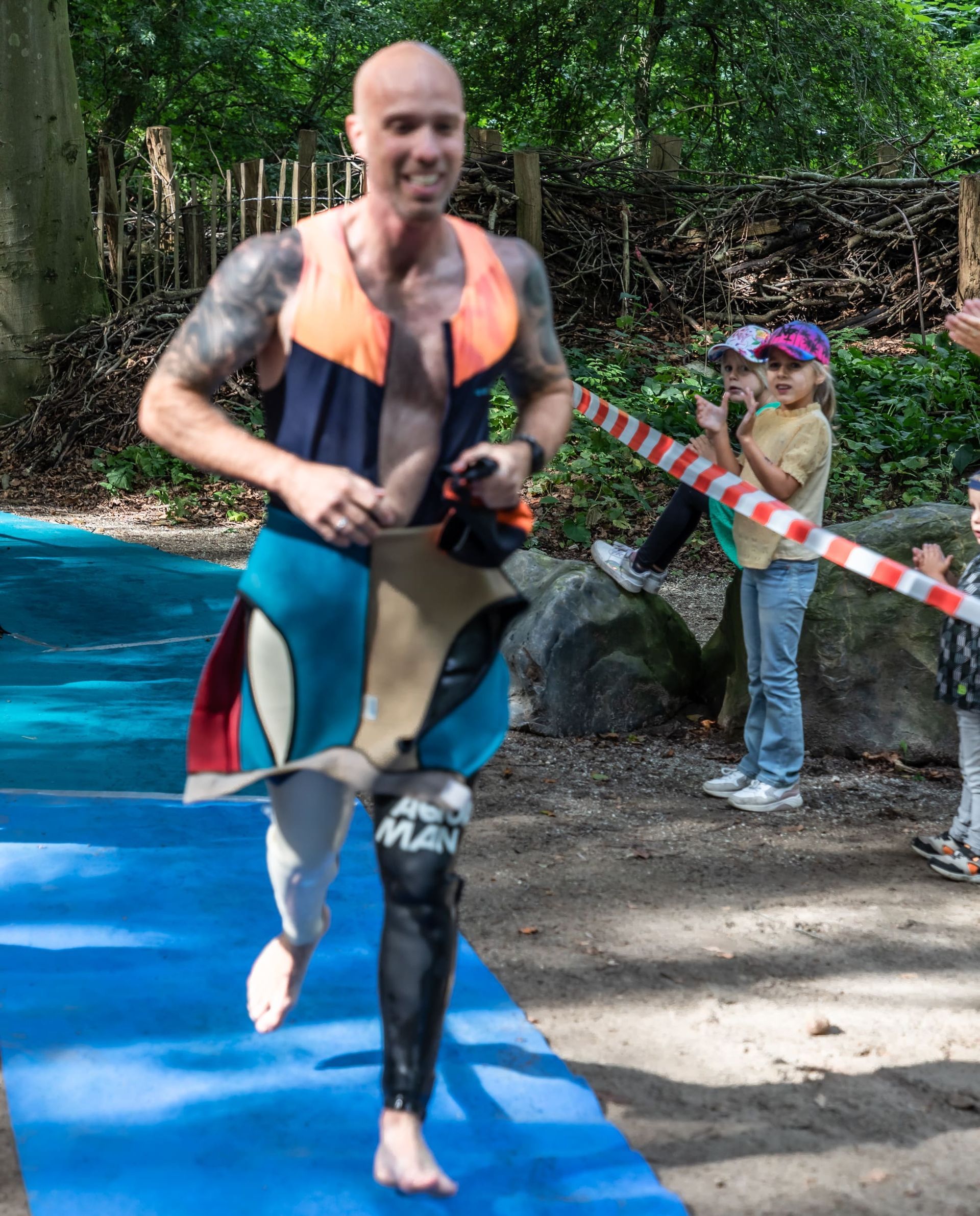 Een man in een wetsuit rent op een blauwe mat