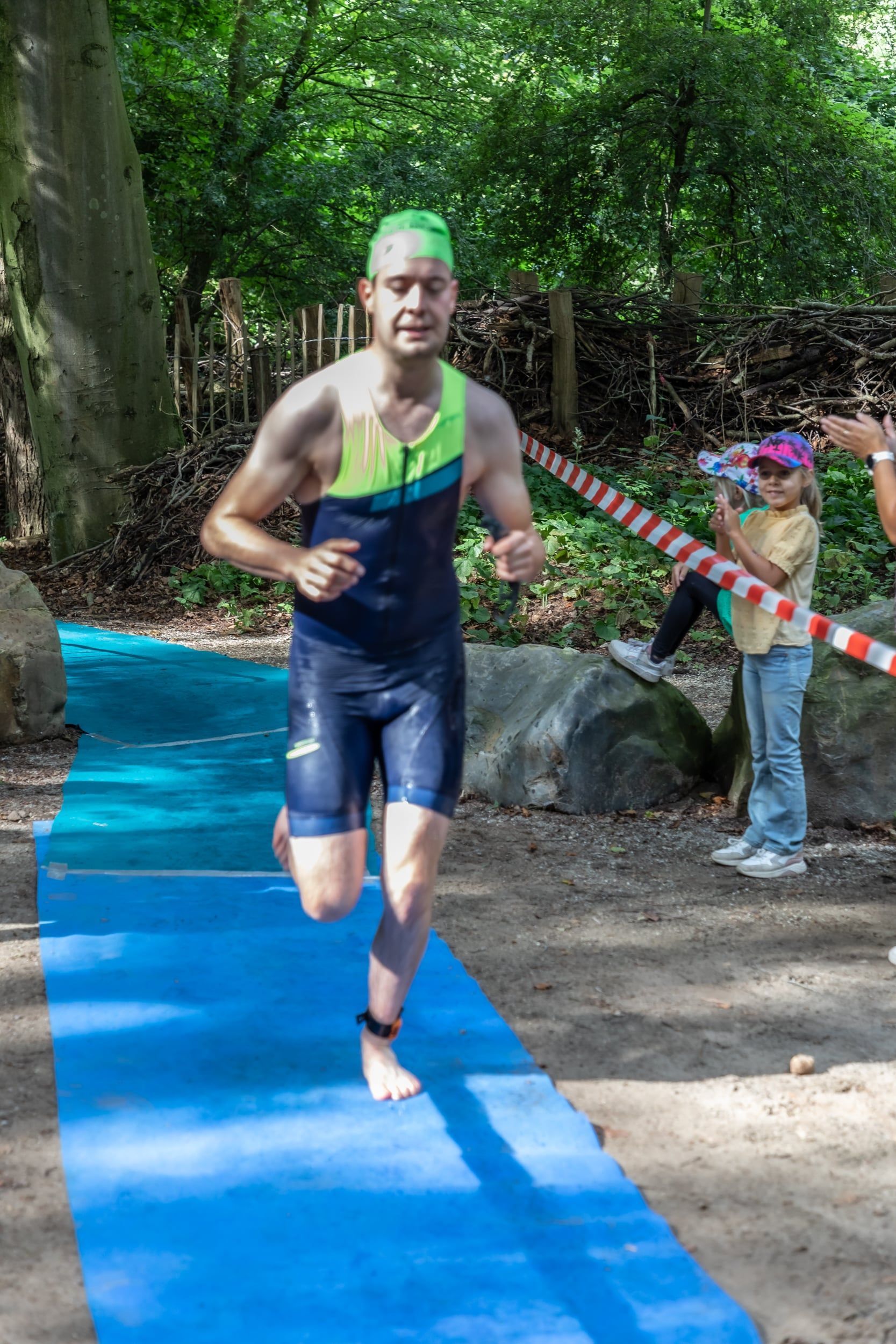 Een man rent op een blauwe mat in het bos.