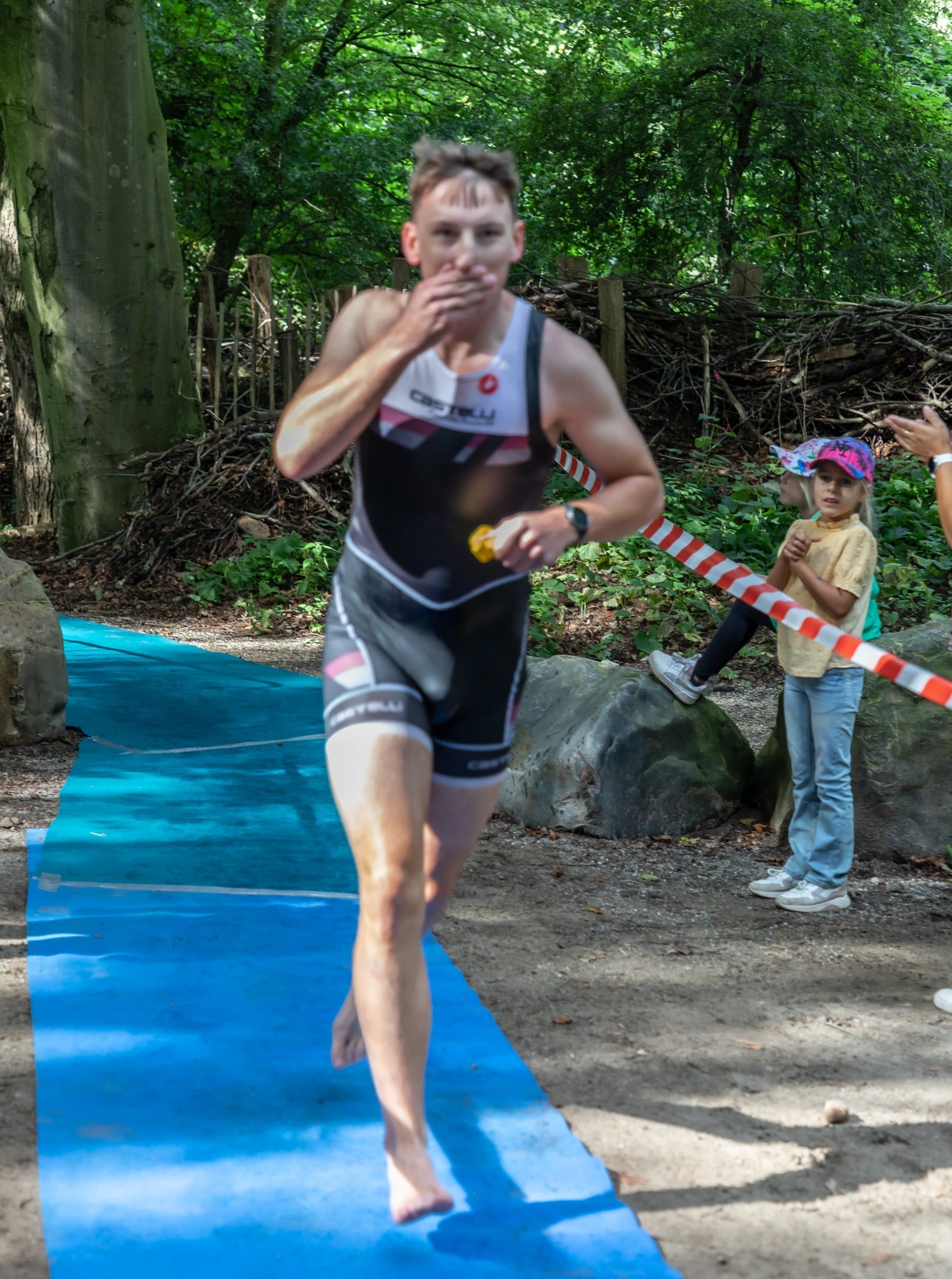 Een man rent op een blauwe mat in het bos.