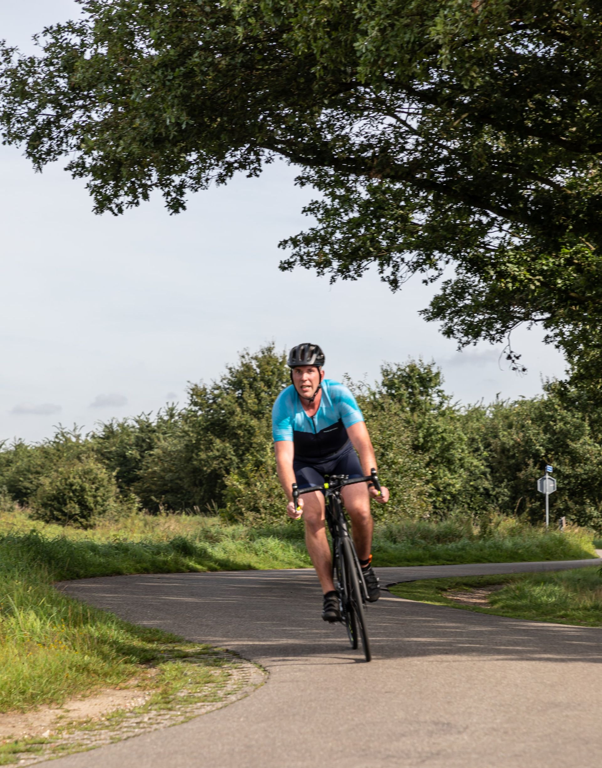 Een man met een helm rijdt op een fiets over de weg.