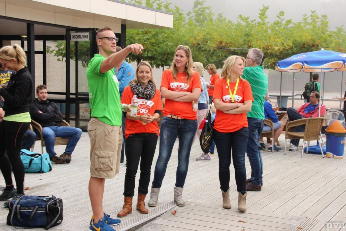 Triathlon Eibergen. Een groep mensen in oranje shirts staat voor een gebouw.