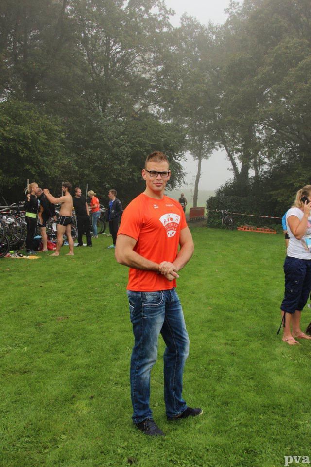 Triathlon Eibergen. Een man in een oranje shirt staat in een grasveld.