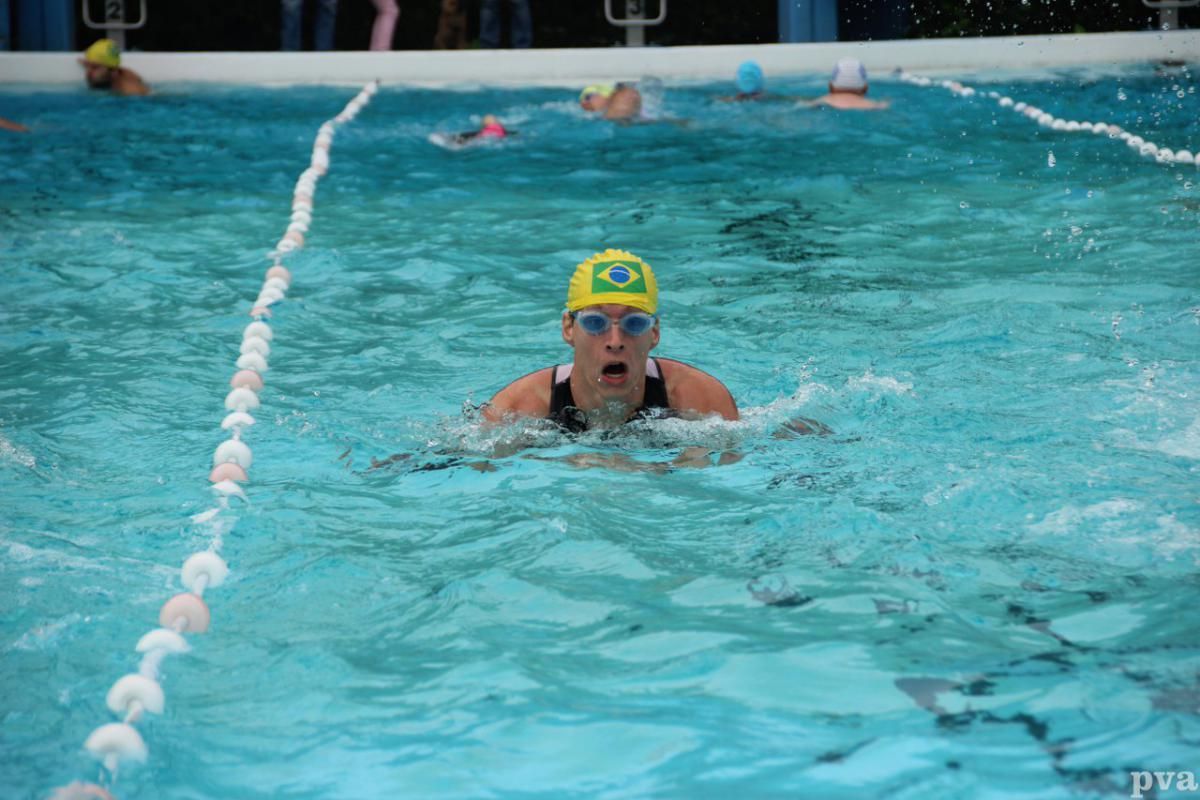Triathlon Eibergen. Een vrouw met een gele badmuts zwemt in een zwembad.