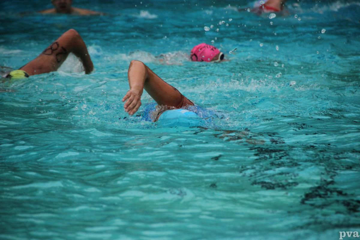 Een groep mensen zwemt in een zwembad.