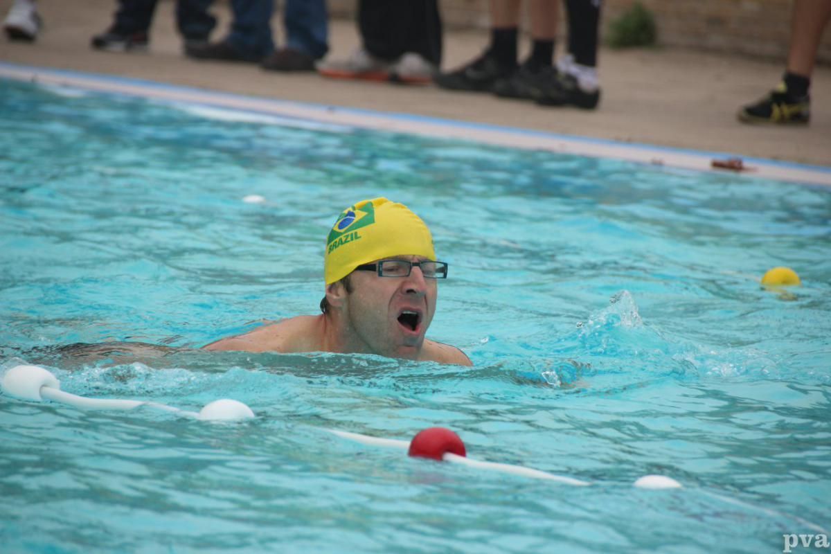 Triathlon Eibergen. Een man met een gele badmuts zwemt in een zwembad.