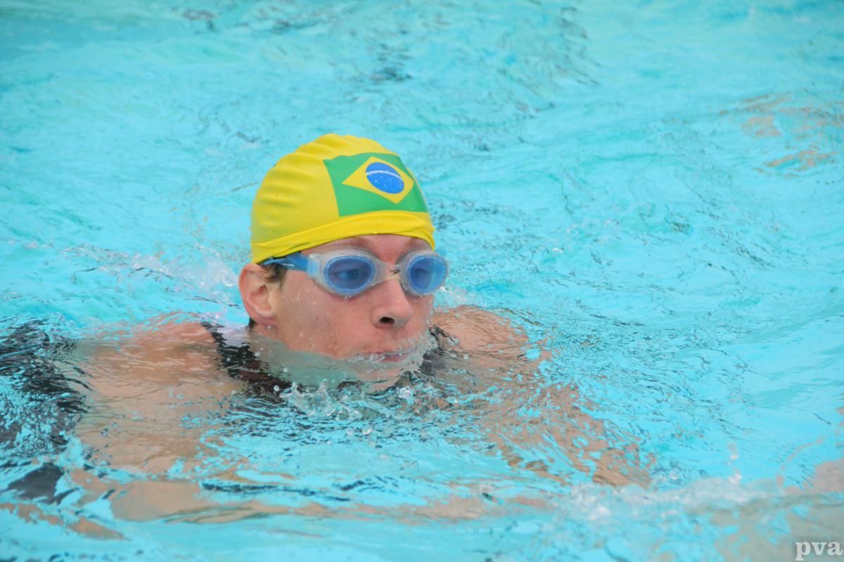 Triathlon Eibergen. Een man met een gele badmuts en een duikbril zwemt in een zwembad.