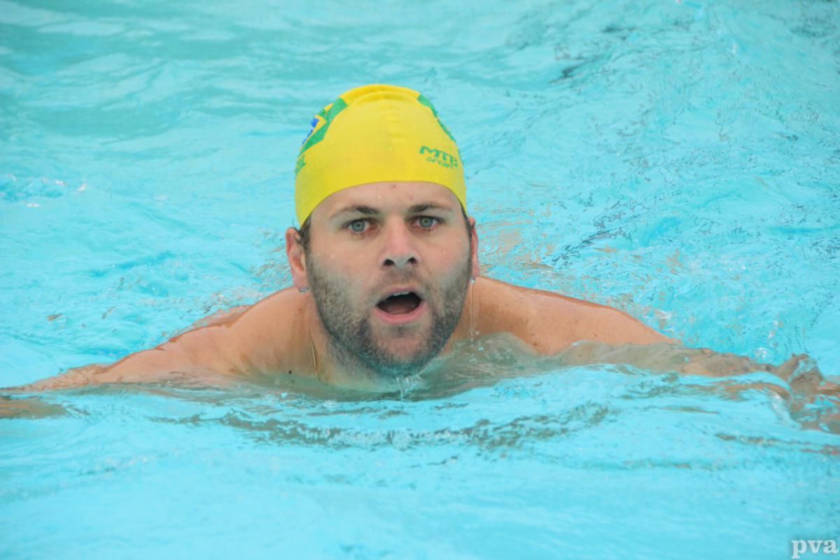 Triathlon Eibergen. Een man zwemt in een zwembad met een gele badmuts op.