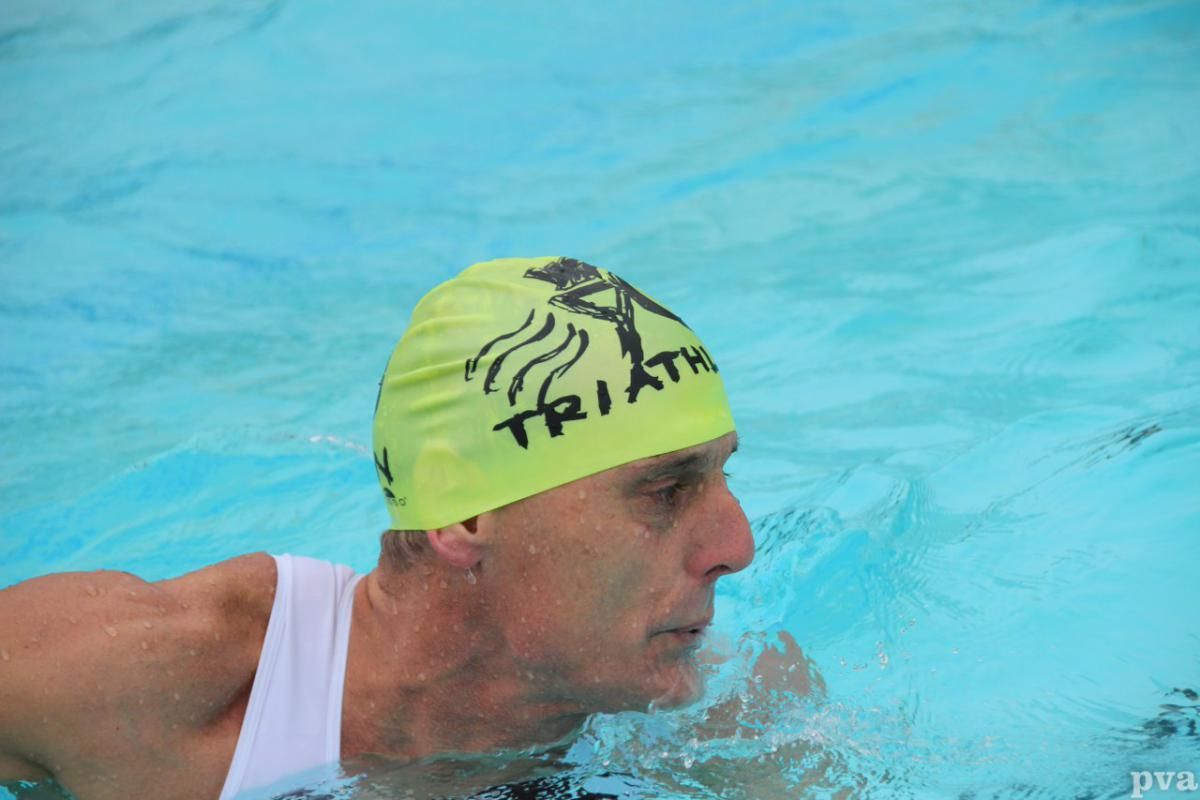 Triathlon Eibergen. Een man met een gele badmuts zwemt in een zwembad.