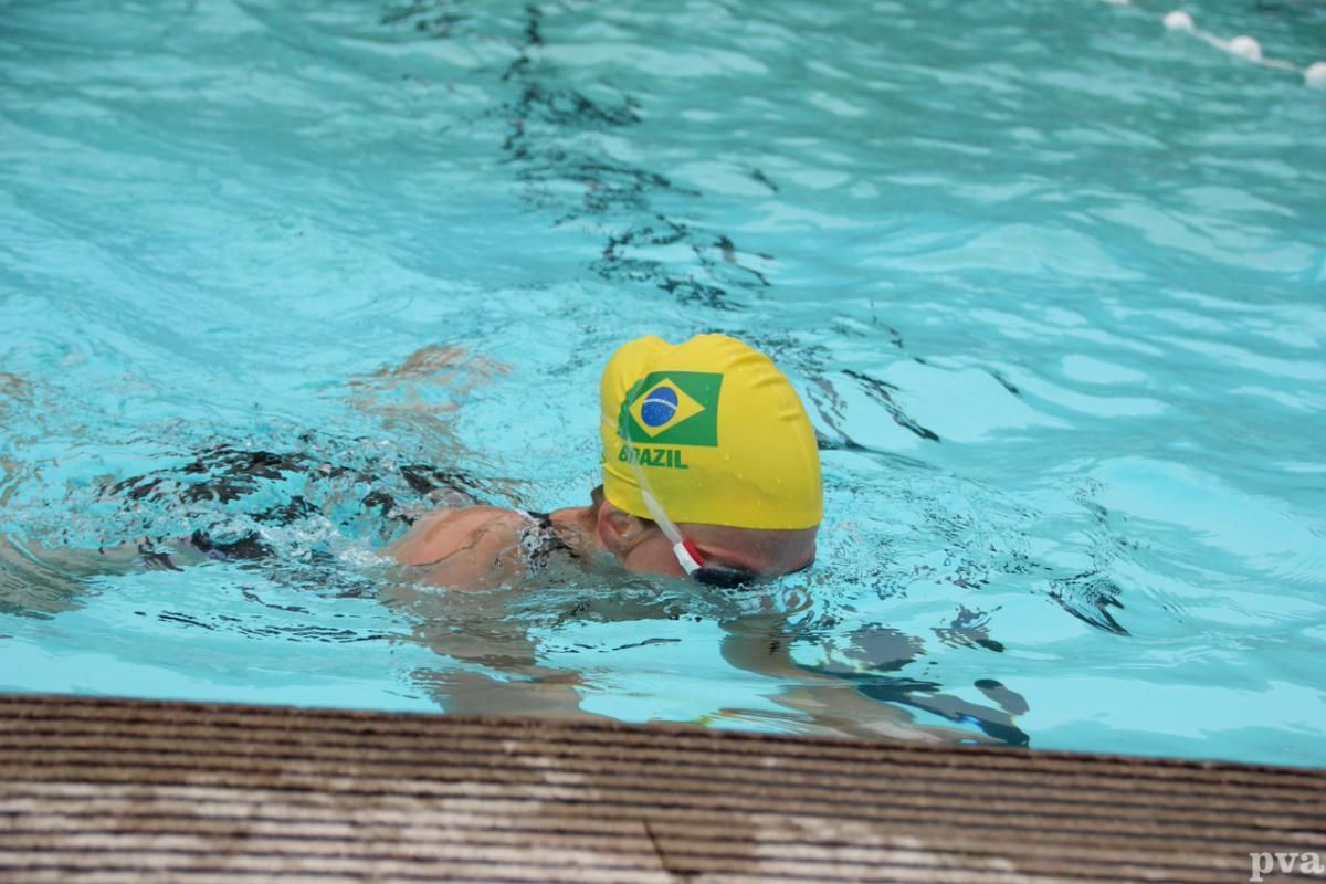 Triathlon Eibergen. Een persoon met een gele badmuts zwemt in een zwembad.