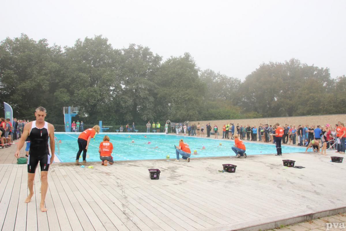 Triathlon Eibergen. Een groep mensen staat rond een zwembad.