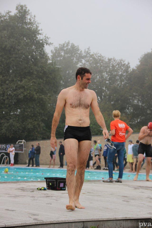 Triathlon Eibergen. Een man zonder shirt in zwembroek staat op de rand van een zwembad.