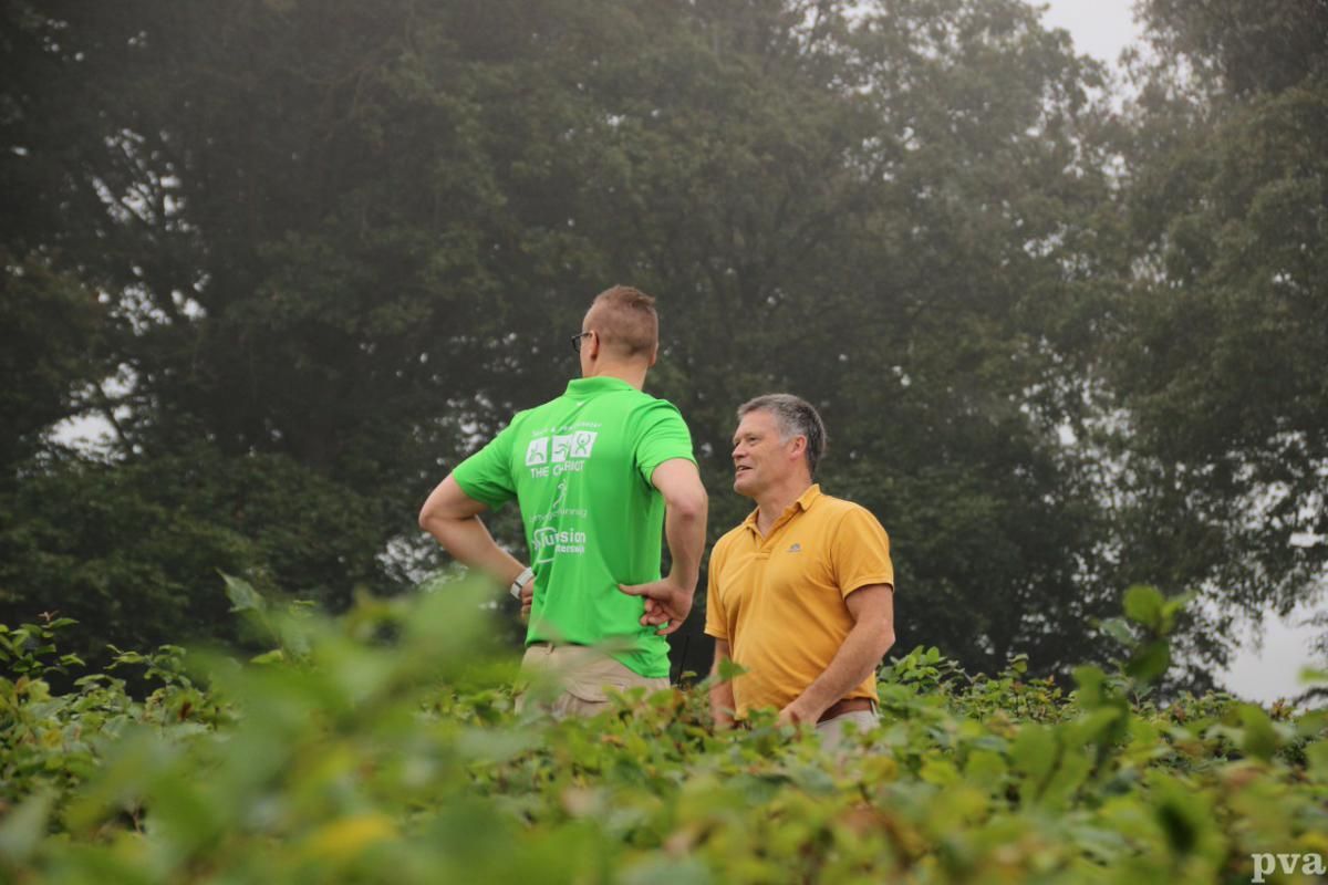 Triathlon Eibergen. Twee mannen staan ​​in een veld met elkaar te praten. Een van de mannen draagt ​​een groen shirt.