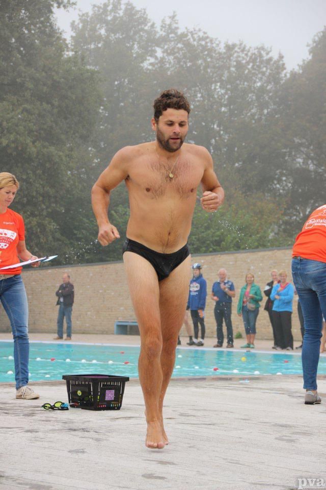 Triathlon Eibergen. Een man zonder shirt in zwembroek rent naar een zwembad.