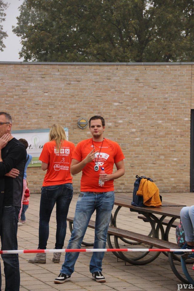Triathlon Eibergen. Een man in een oranje shirt staat voor een picknicktafel.