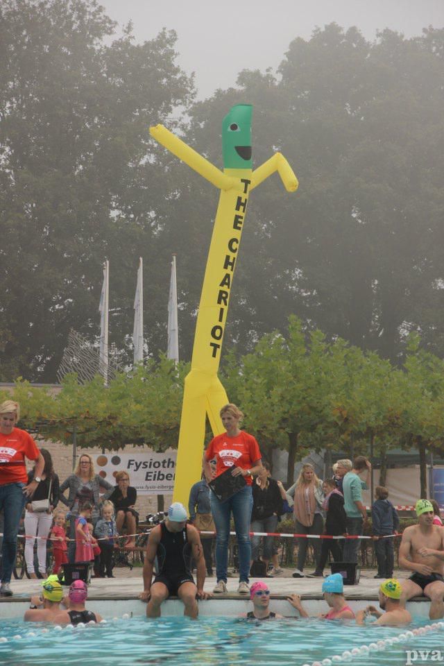 Triathlon Eibergen. Een groep mensen zwemt in een zwembad met een opblaasbare man die de strijdwagen zegt