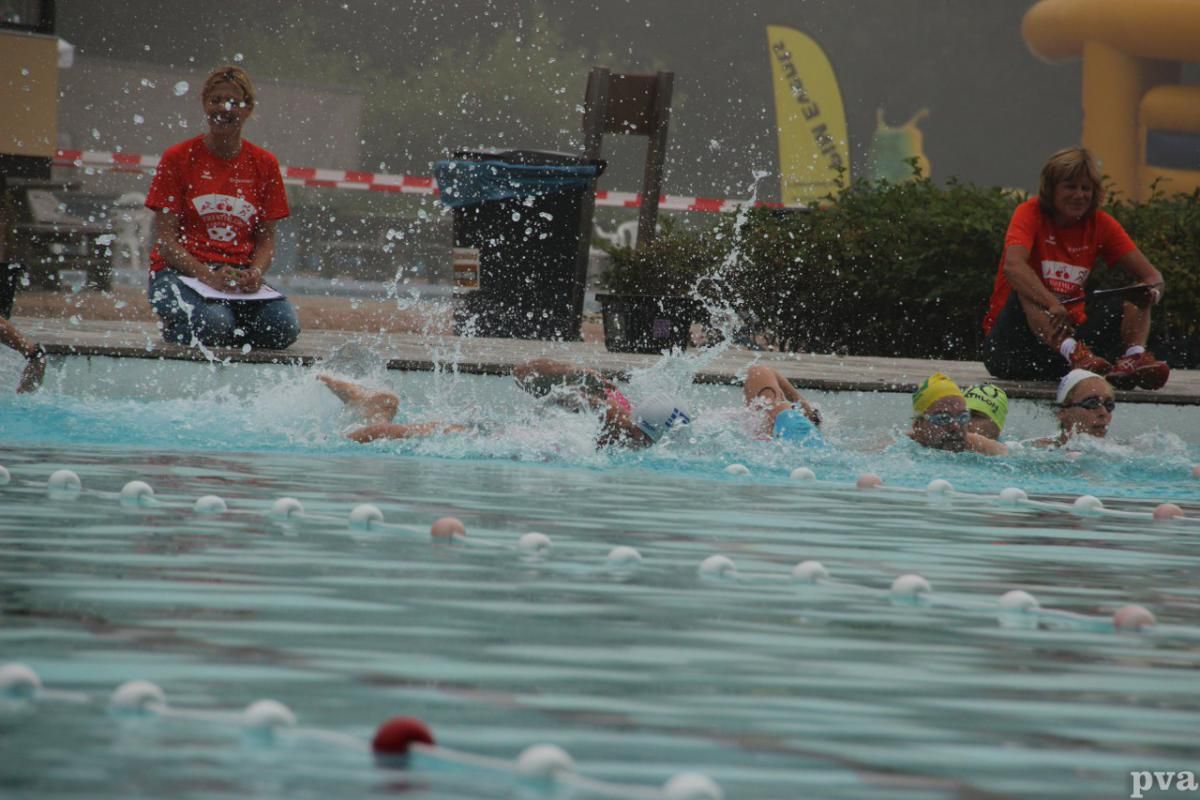 Triathlon Eibergen. Een groep mensen zwemt in een zwembad in de regen.