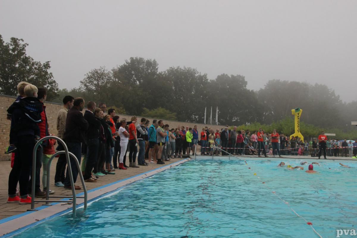 Triathlon Eibergen. Een groep mensen staat op een mistige dag rond een zwembad.